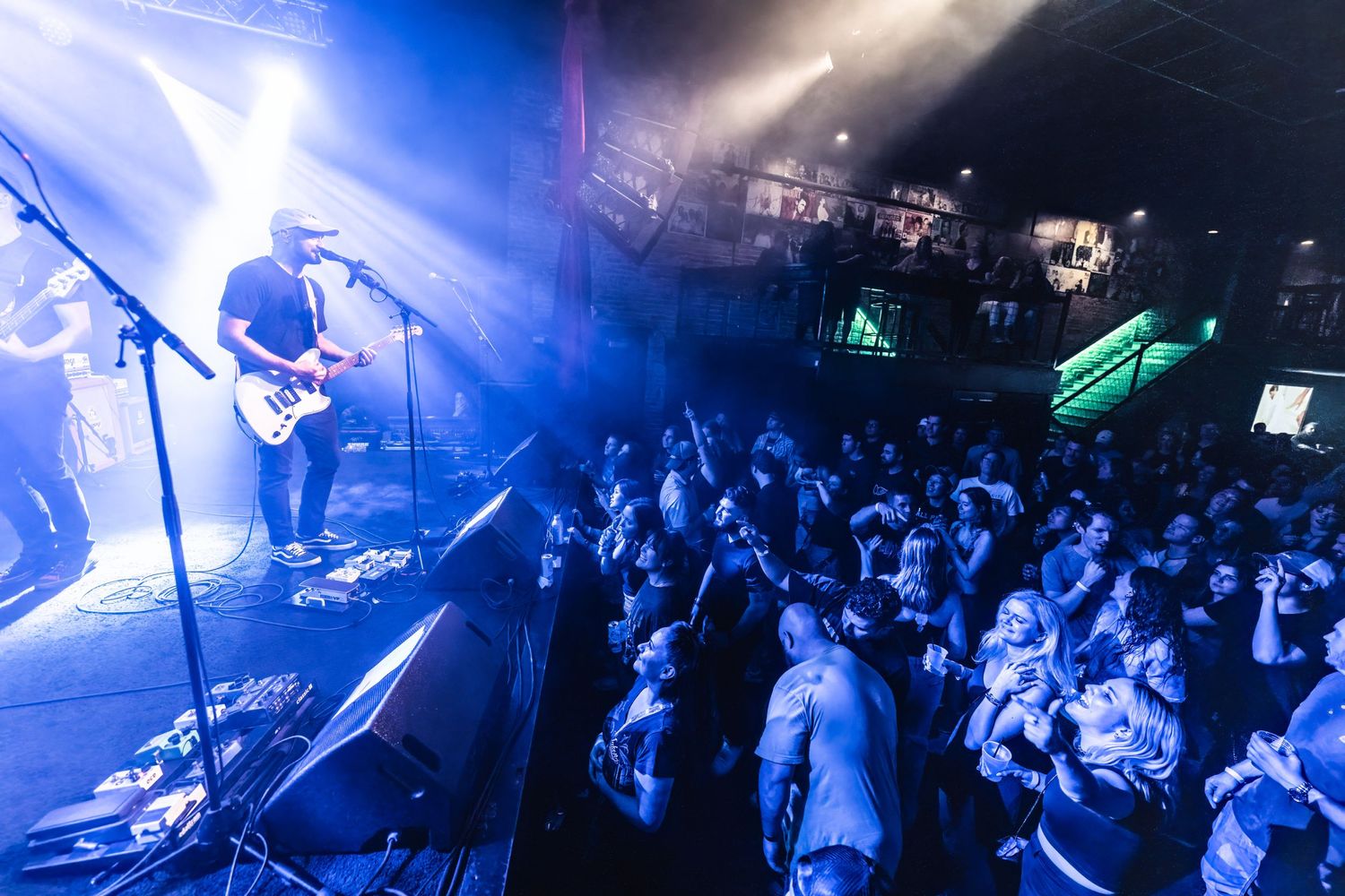Wide shot of band performing on stage with crowd silhouetted under blue lighting.