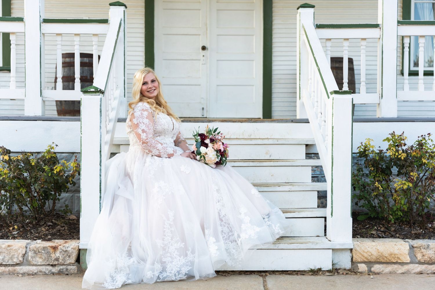 Traditional bridal portrait on white porch steps with floral bouquet.