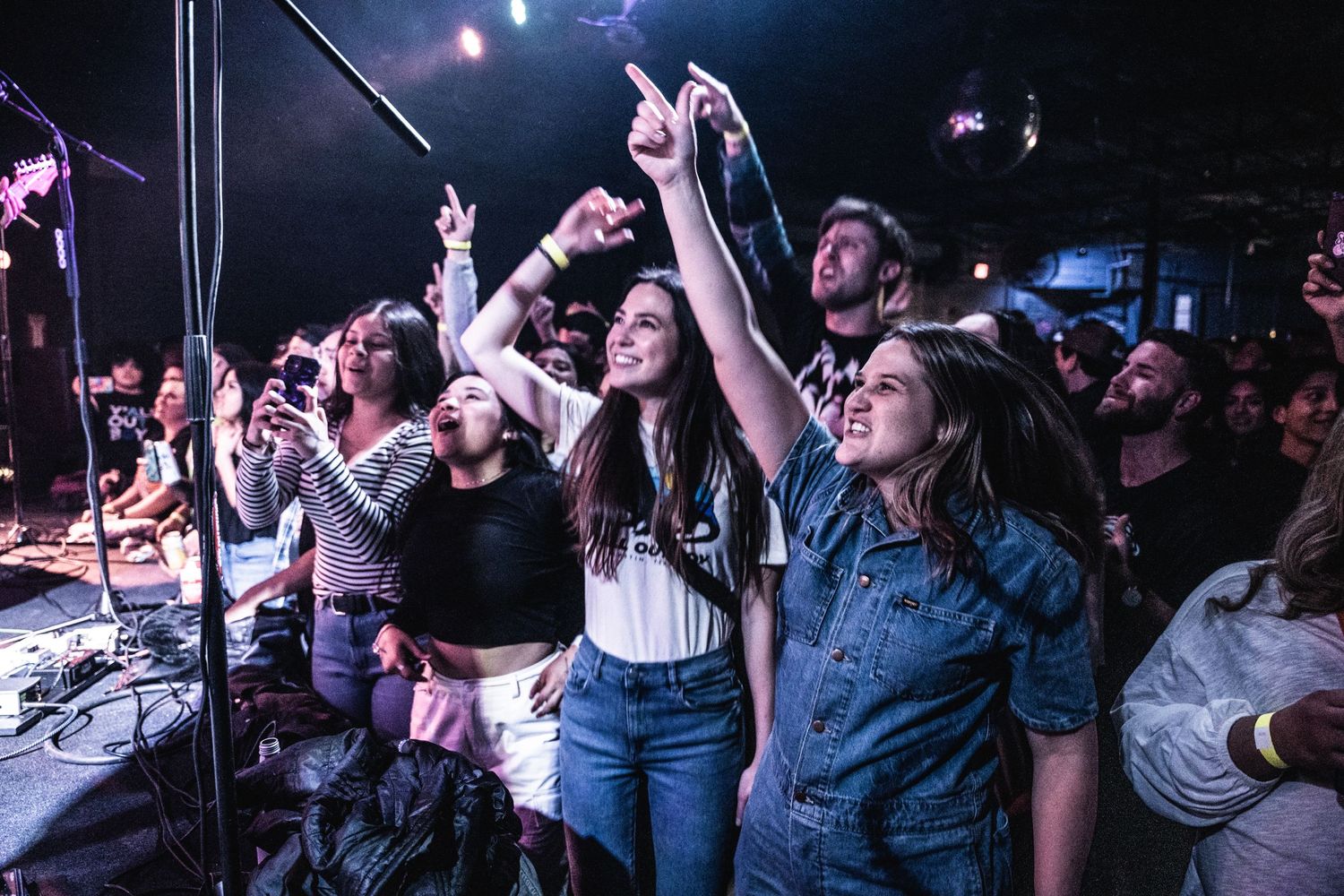 Enthusiastic fans point and sing along at a live music performance.