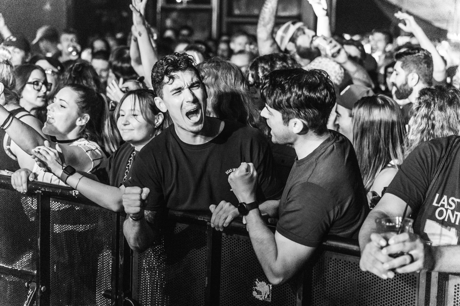 Black and white photo captures passionate crowd reaction at a rock concert barrier.