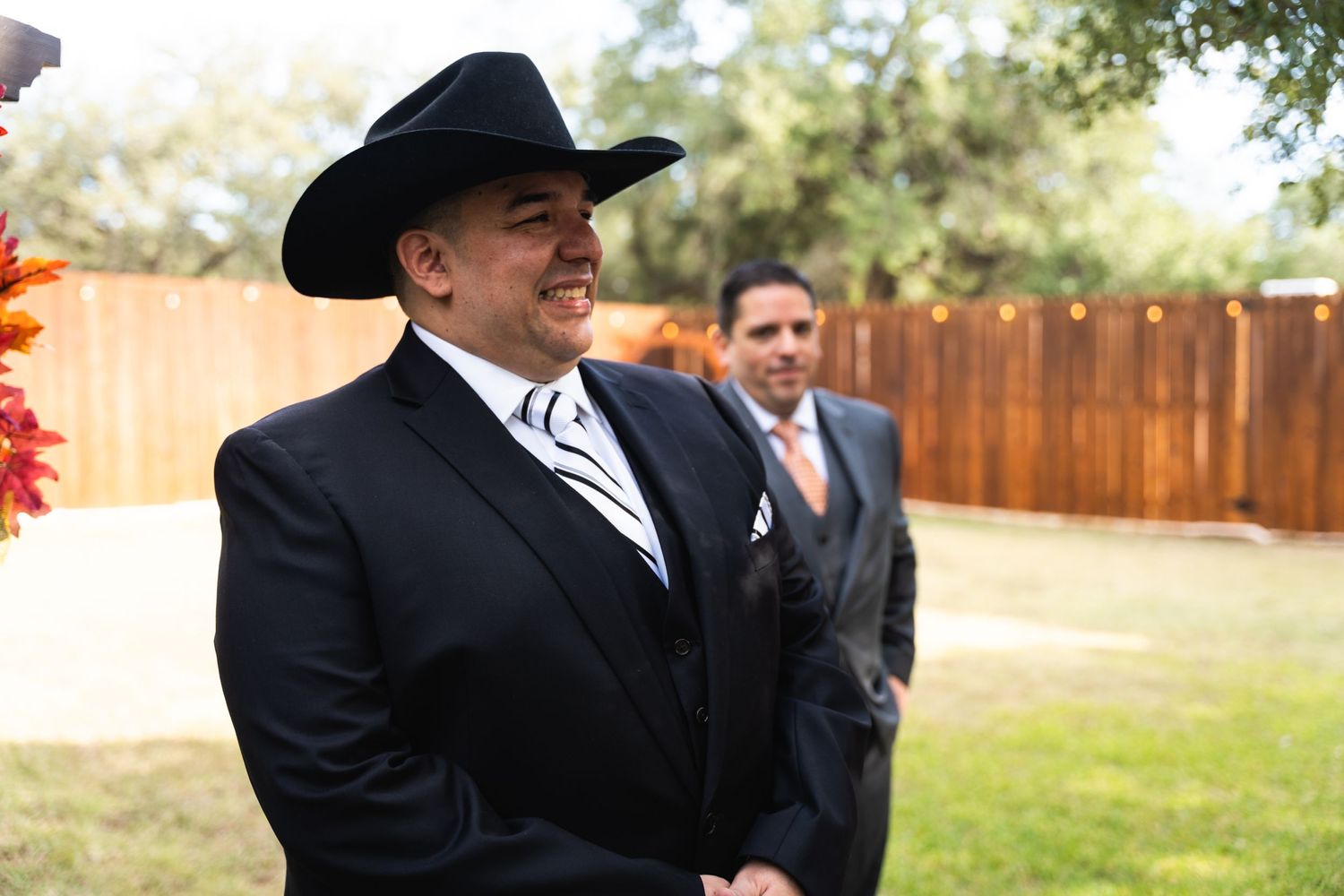 A man in western formal wear smiles during an outdoor celebration.
