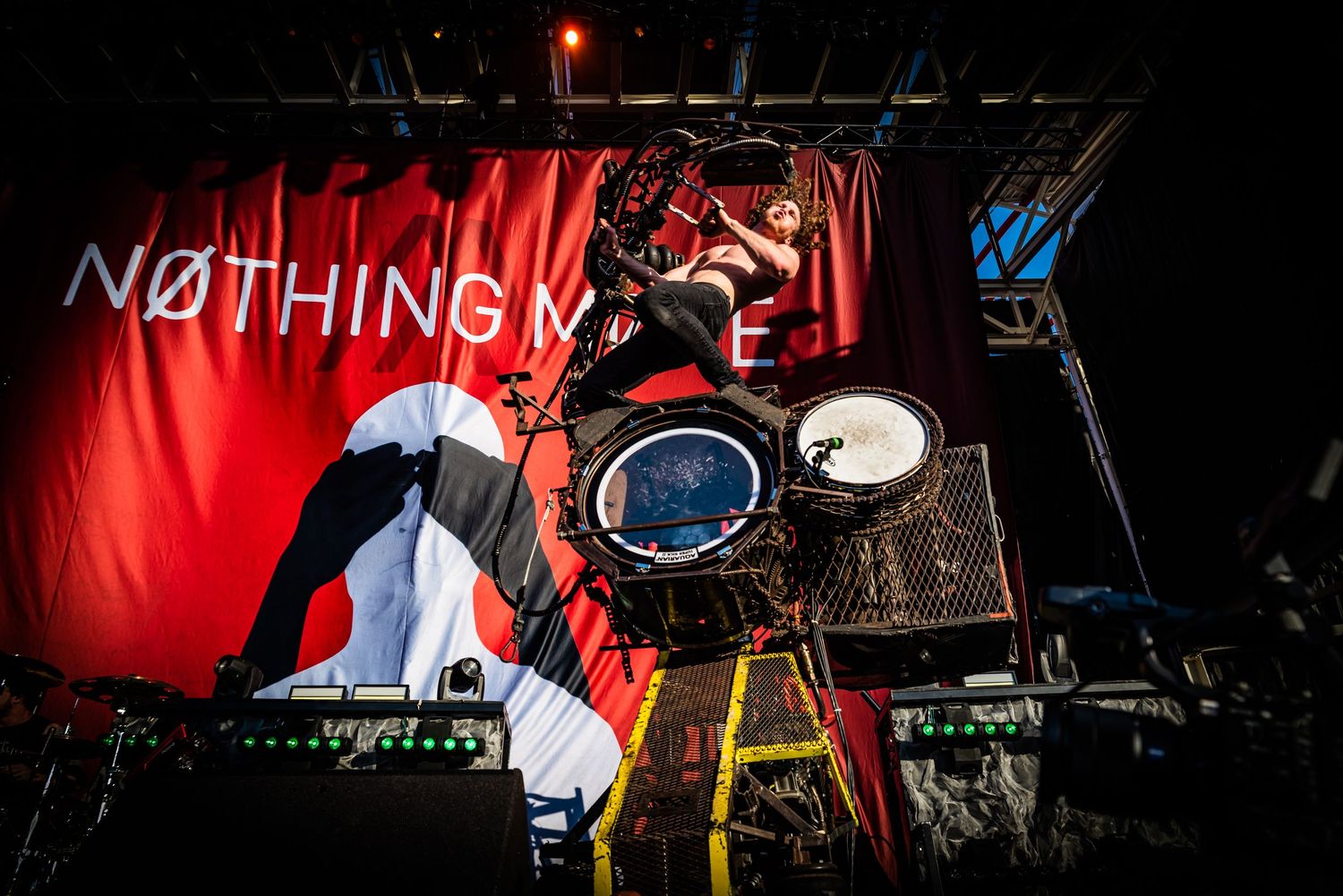 A dramatic concert stage performance with red lighting and silhouetted figures against a dark background.