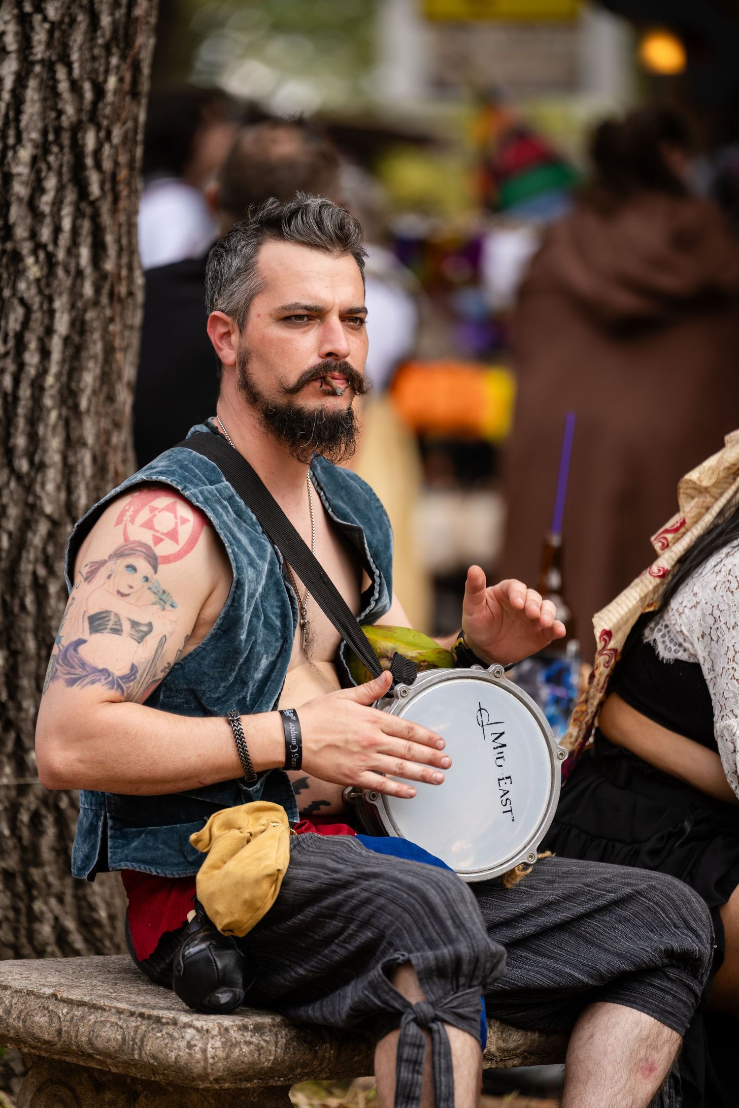 Musician plays a traditional banjo while sitting outdoors at a folk music festival.