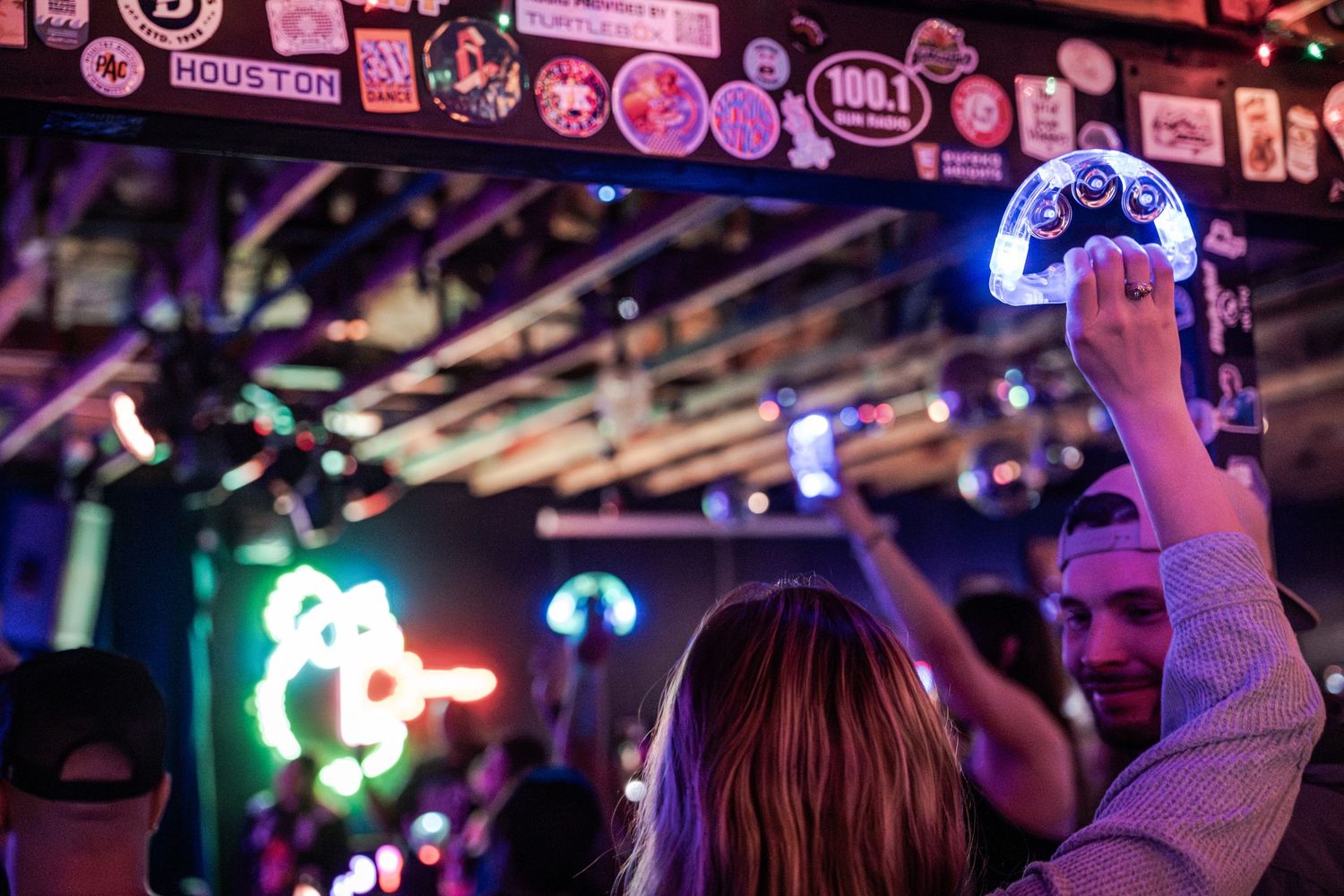 People dancing and enjoying themselves in a vibrant nightclub with colorful neon lighting and decorations.
