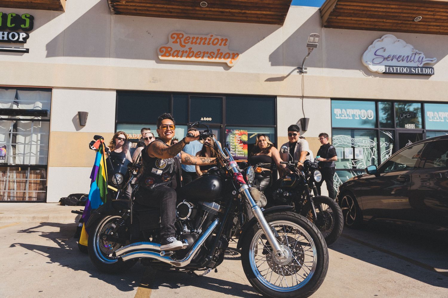 Vintage motorcycles lined up in front of storefronts with retro signage and classic styling.