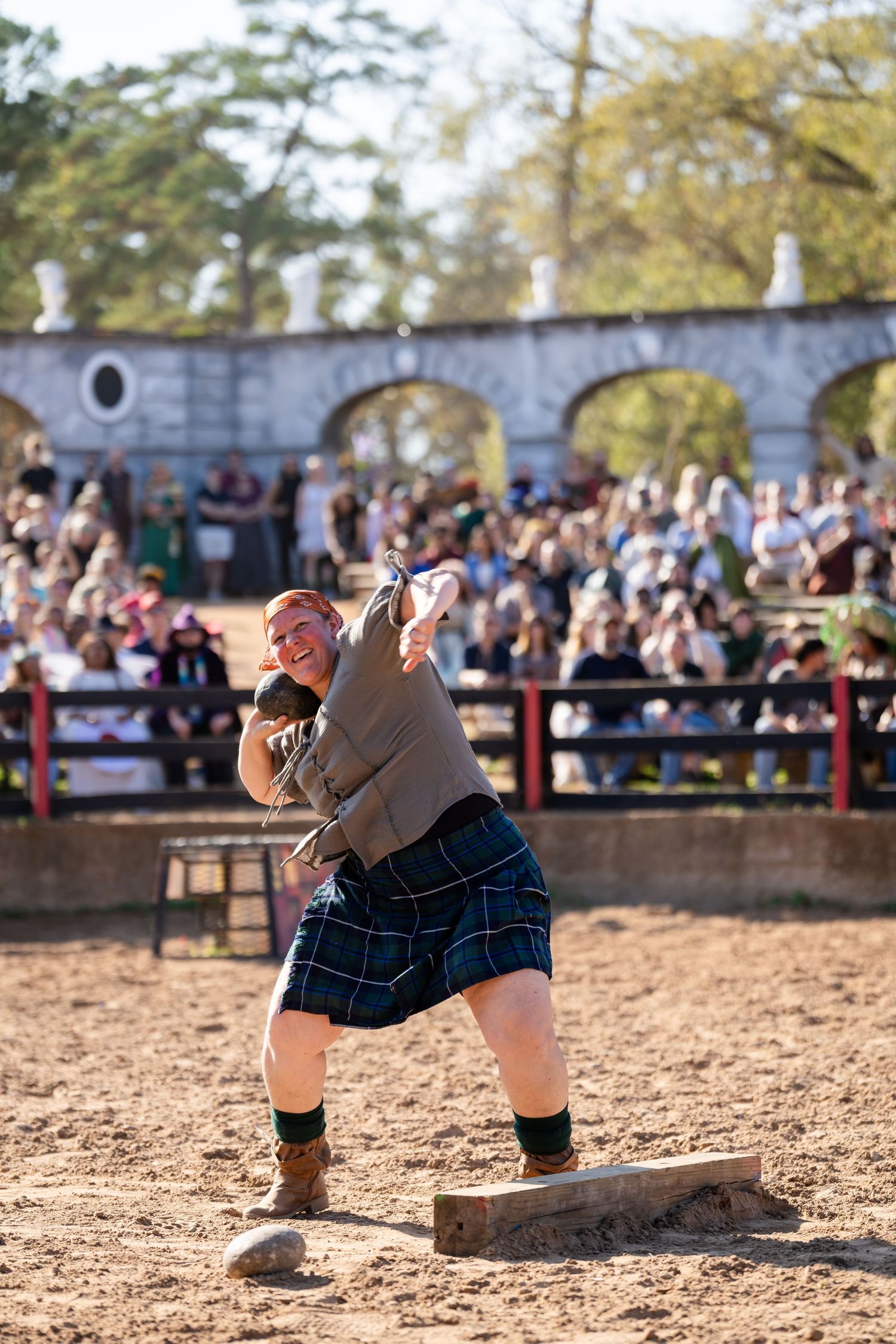 A participant in traditional Scottish highland games performs the stone throw event in an outdoor arena.