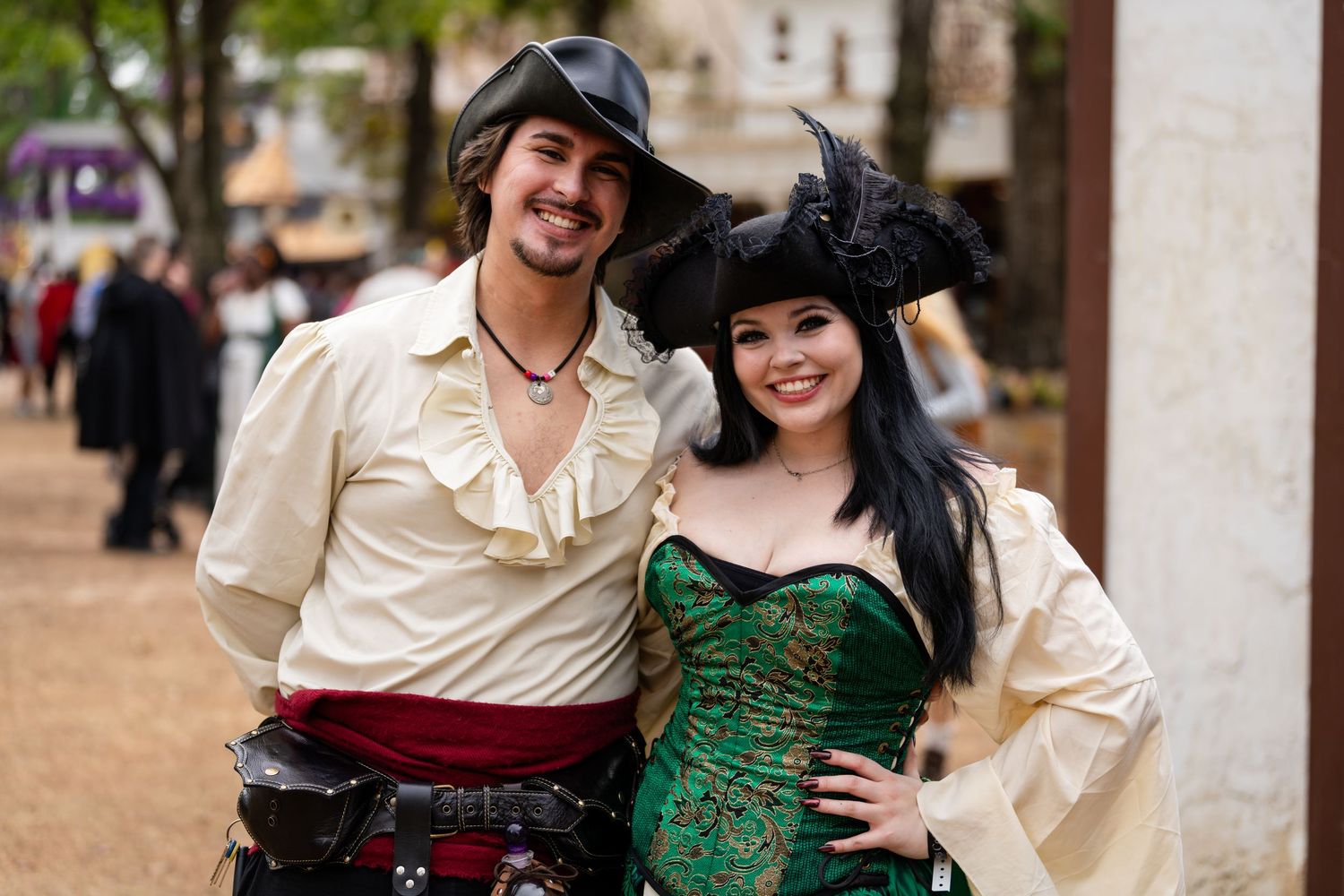 Couple in Renaissance festival costumes posing together outdoors at a medieval fair.