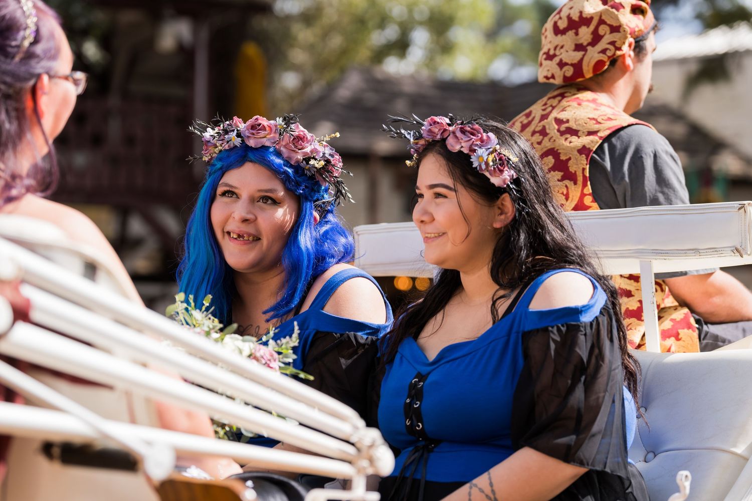People in blue outfits enjoy a festive celebration outdoors during a sunny day.