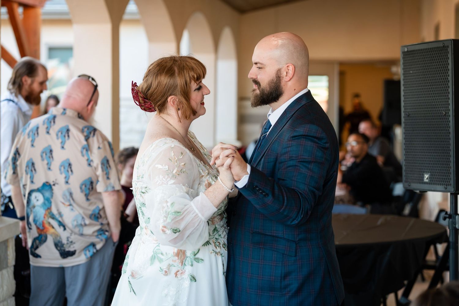 A couple shares an intimate dance moment at their wedding reception while guests look on in the background.