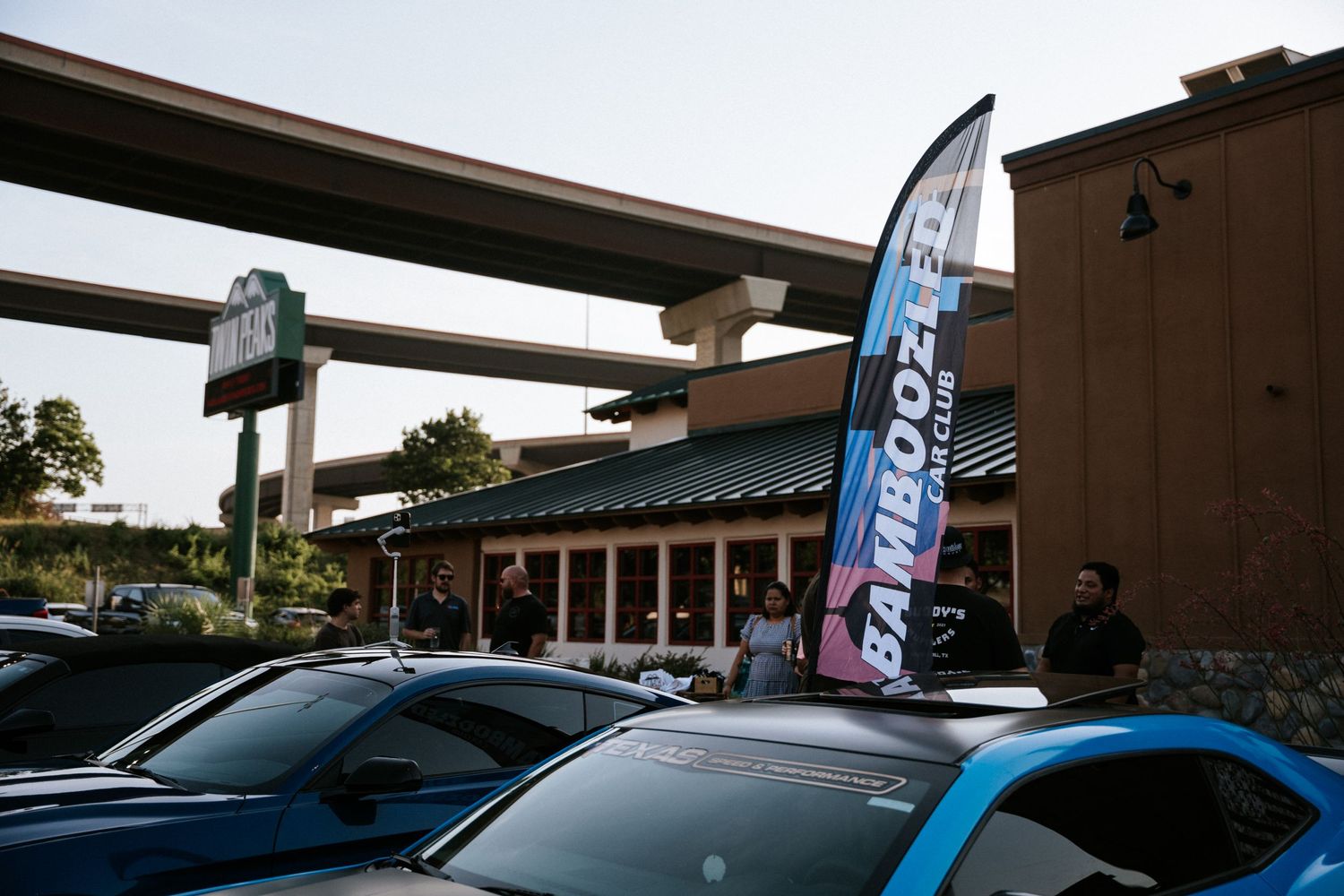 A car dealership exterior with feather flags and parked vehicles at dusk.