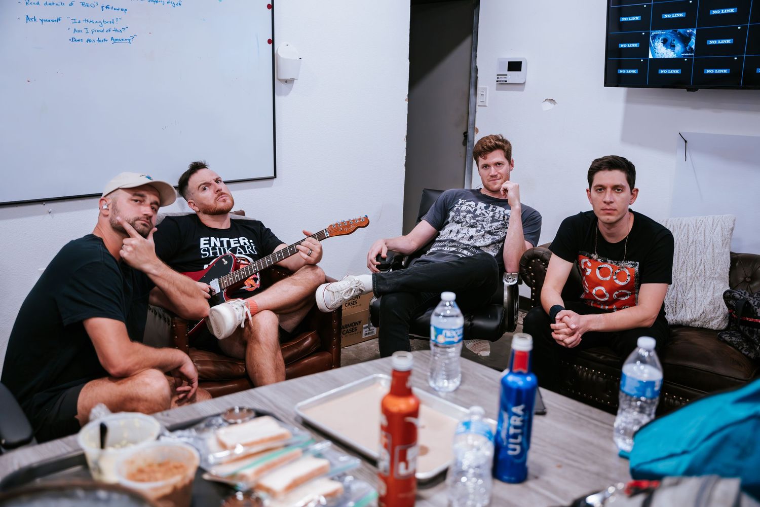 A casual group gathering in a room with water bottles and snacks on the table.