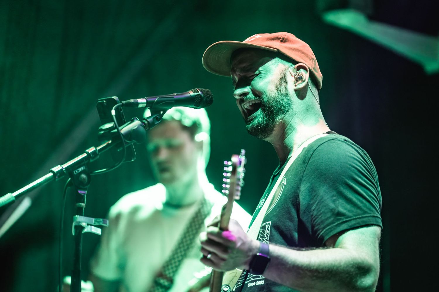 Musicians perform under moody green stage lighting during live concert.