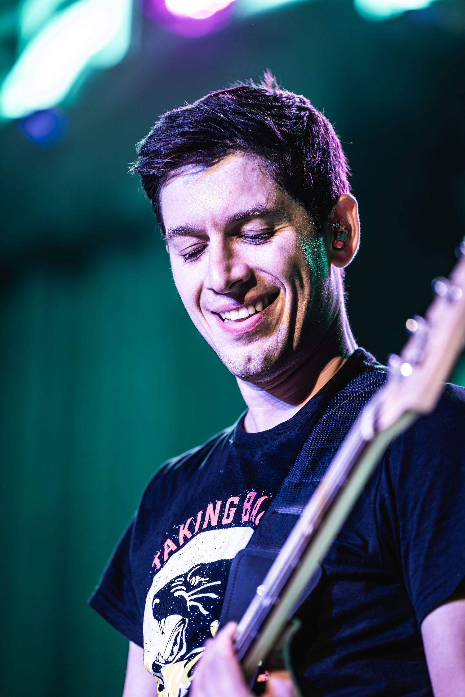 Bassist performing on stage with green lighting effects.
