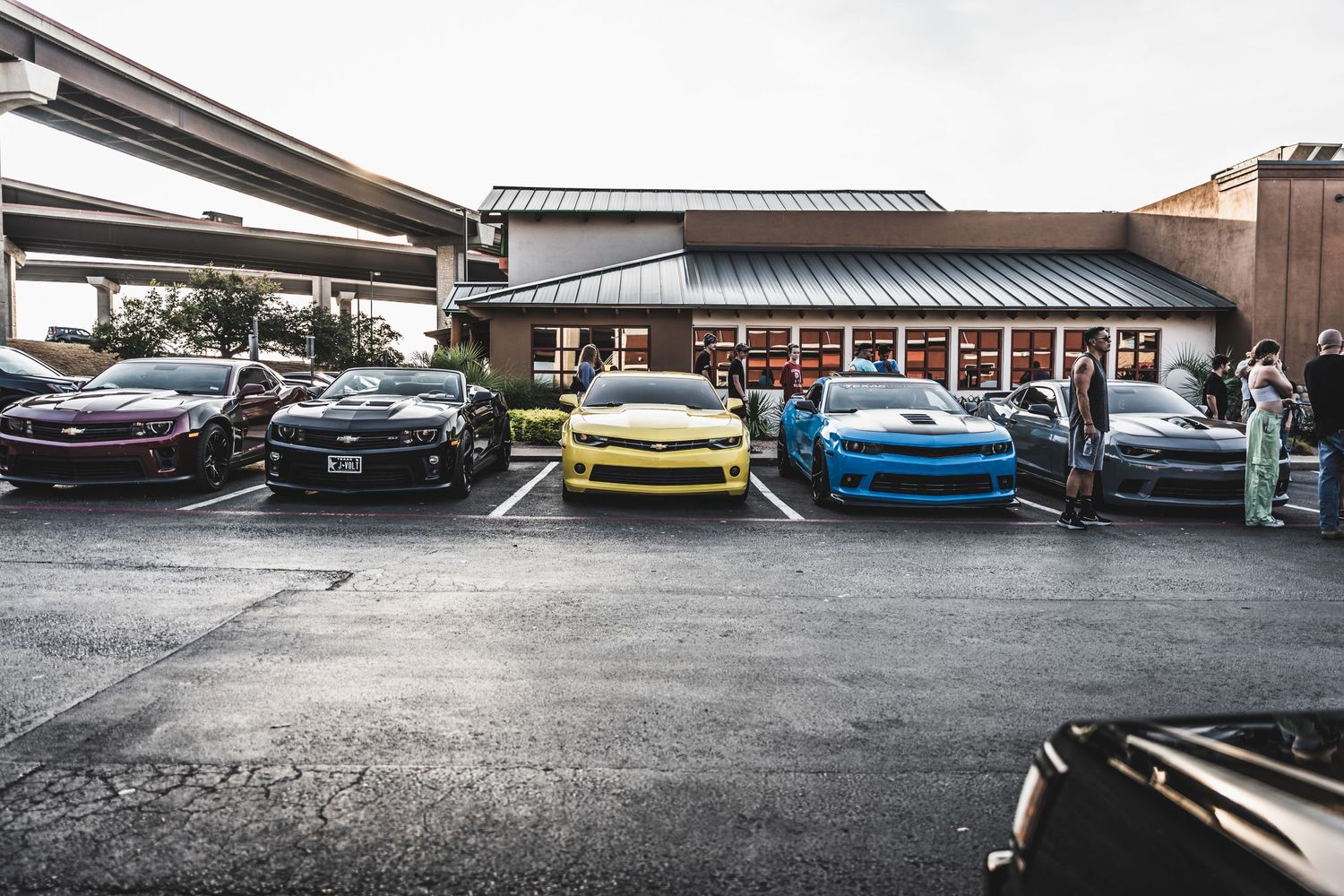Row of colorful sports cars parked outside a commercial building.