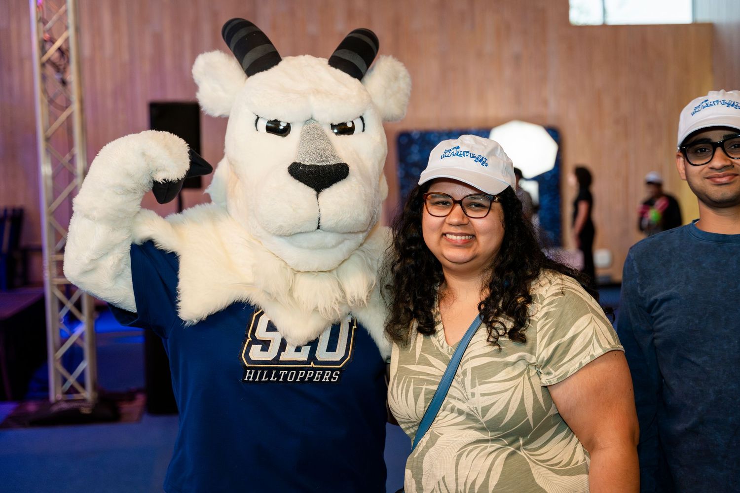 A large white BYU mascot Cosmo the Cougar poses with a visitor at a university event.