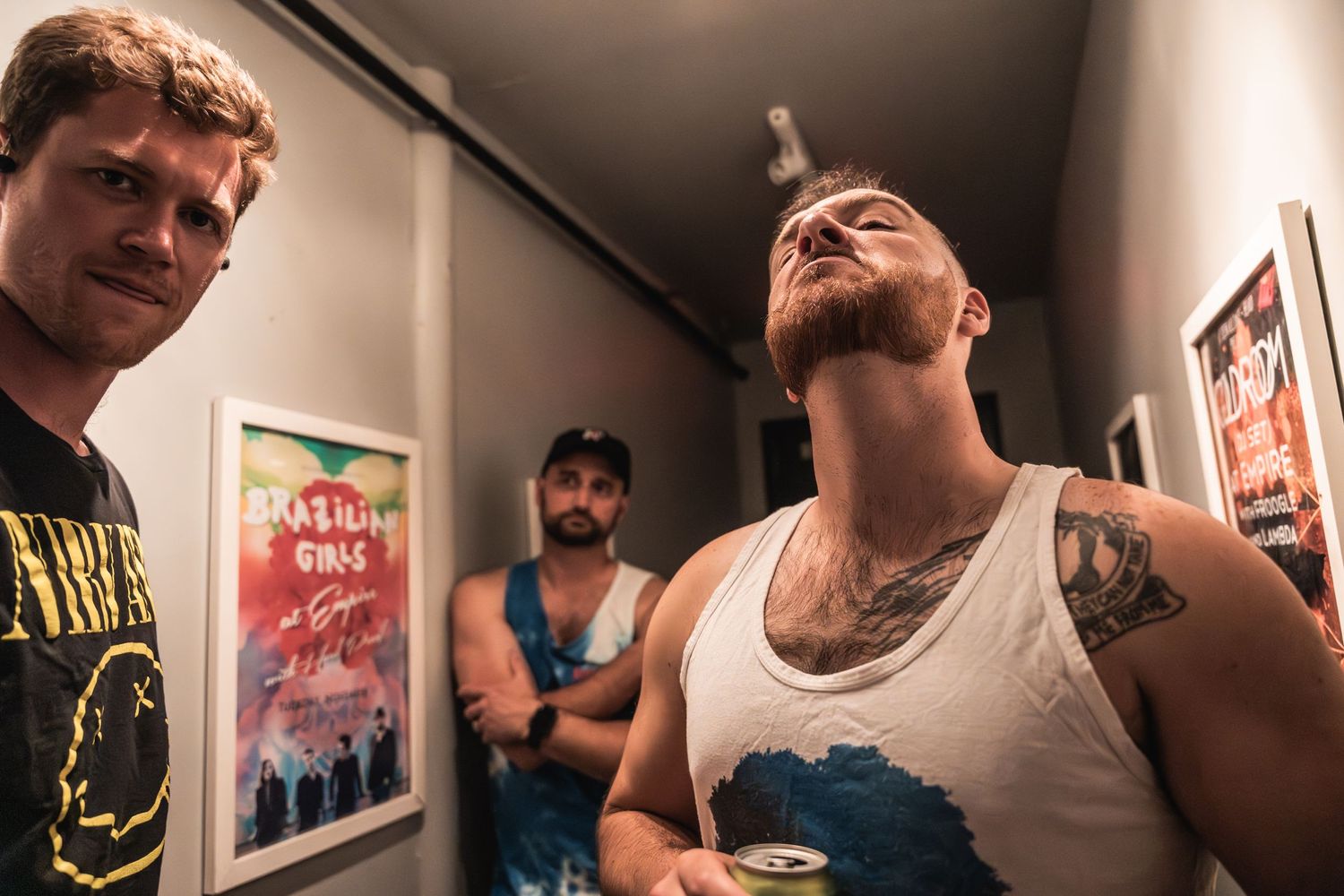 Casual backstage scene with band members in a dimly lit hallway.