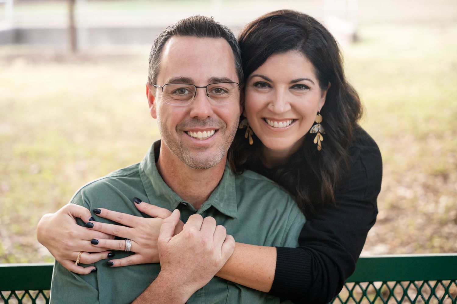 A couple shares a joyful moment together outdoors in casual attire.