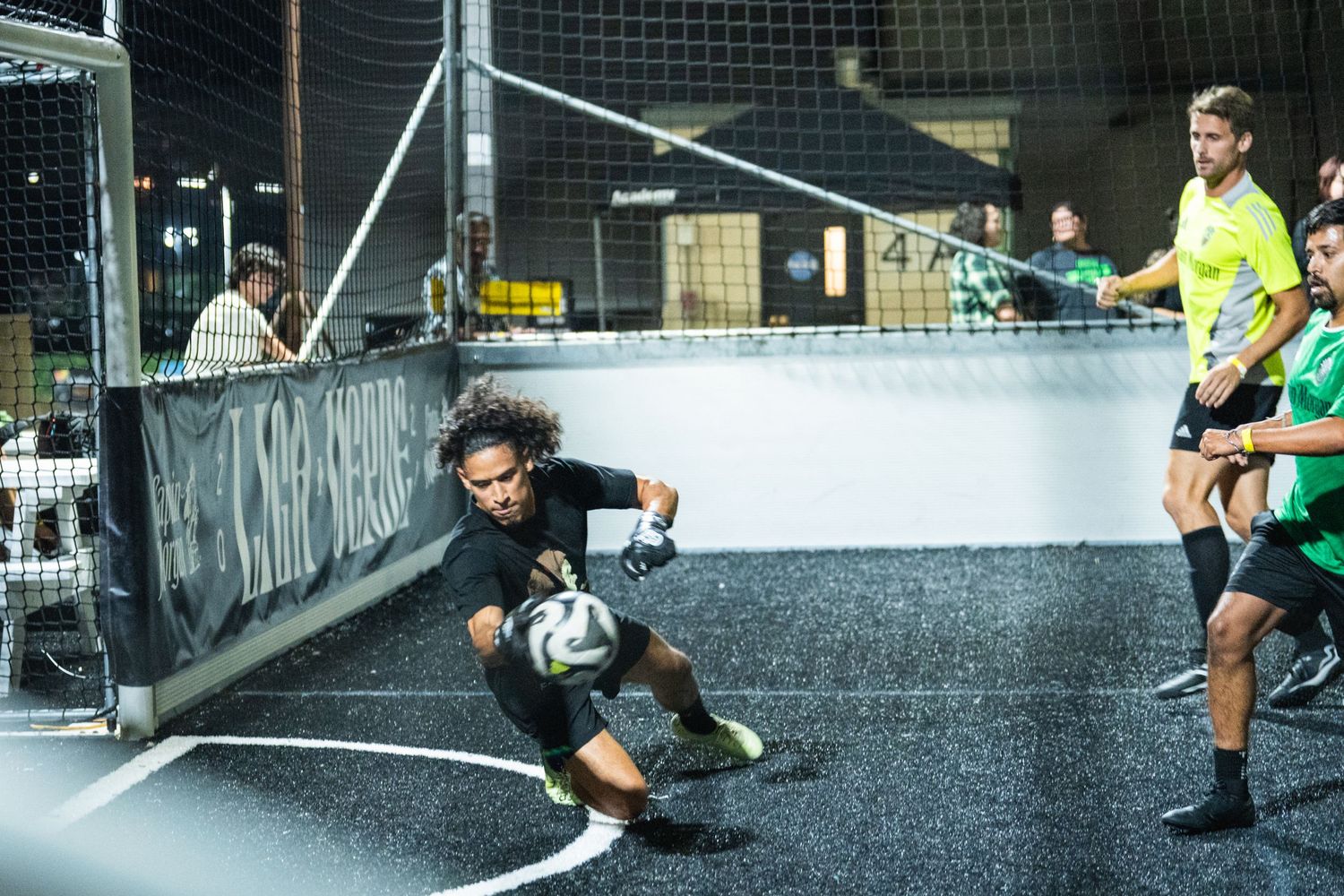 Soccer player makes a diving save during an intense street soccer match on an urban court.