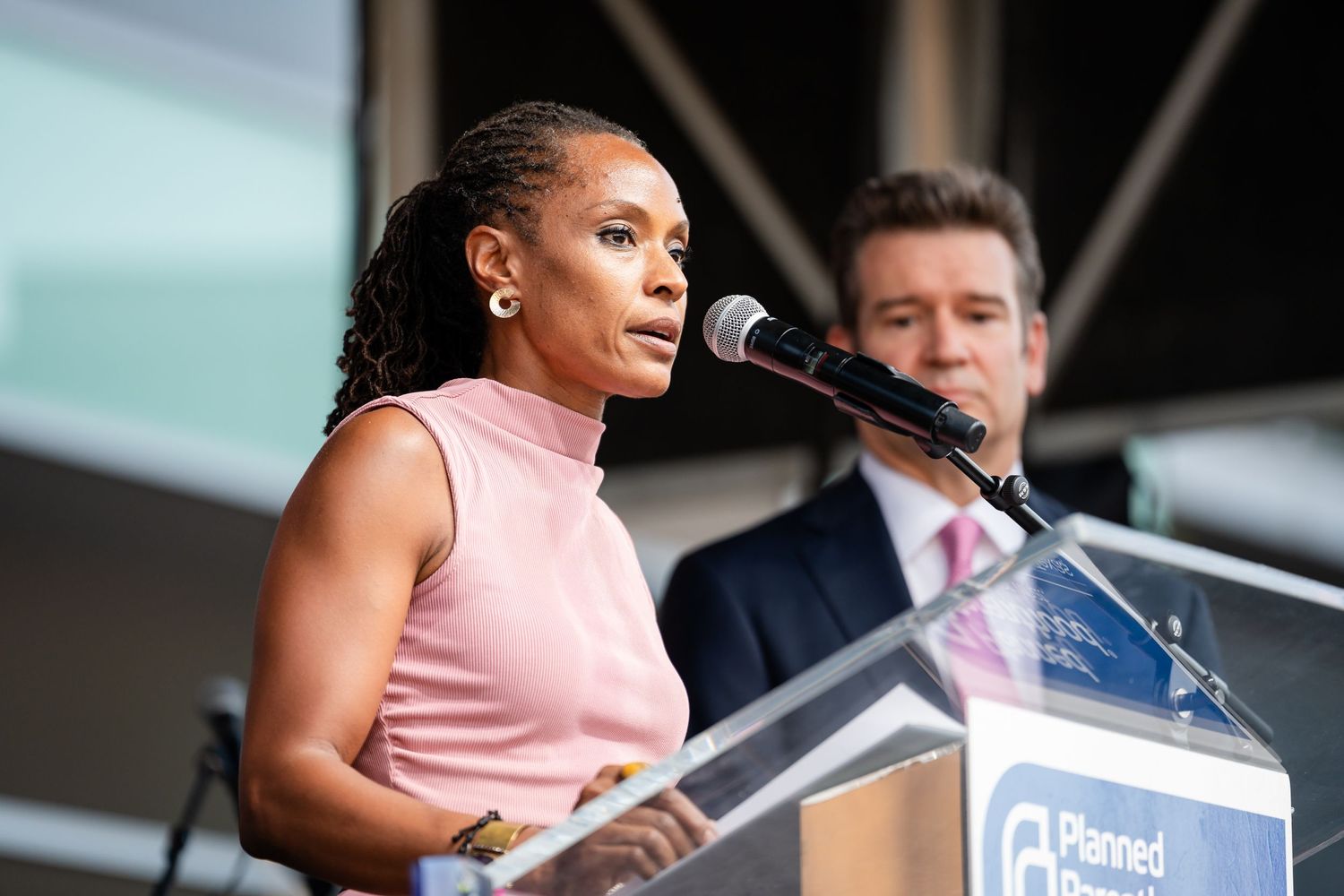 Speakers at podium delivering remarks at outdoor Planned Parenthood event.