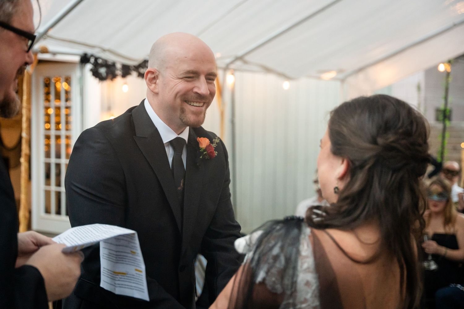Wedding ceremony participants sharing a joyful moment under white tent.