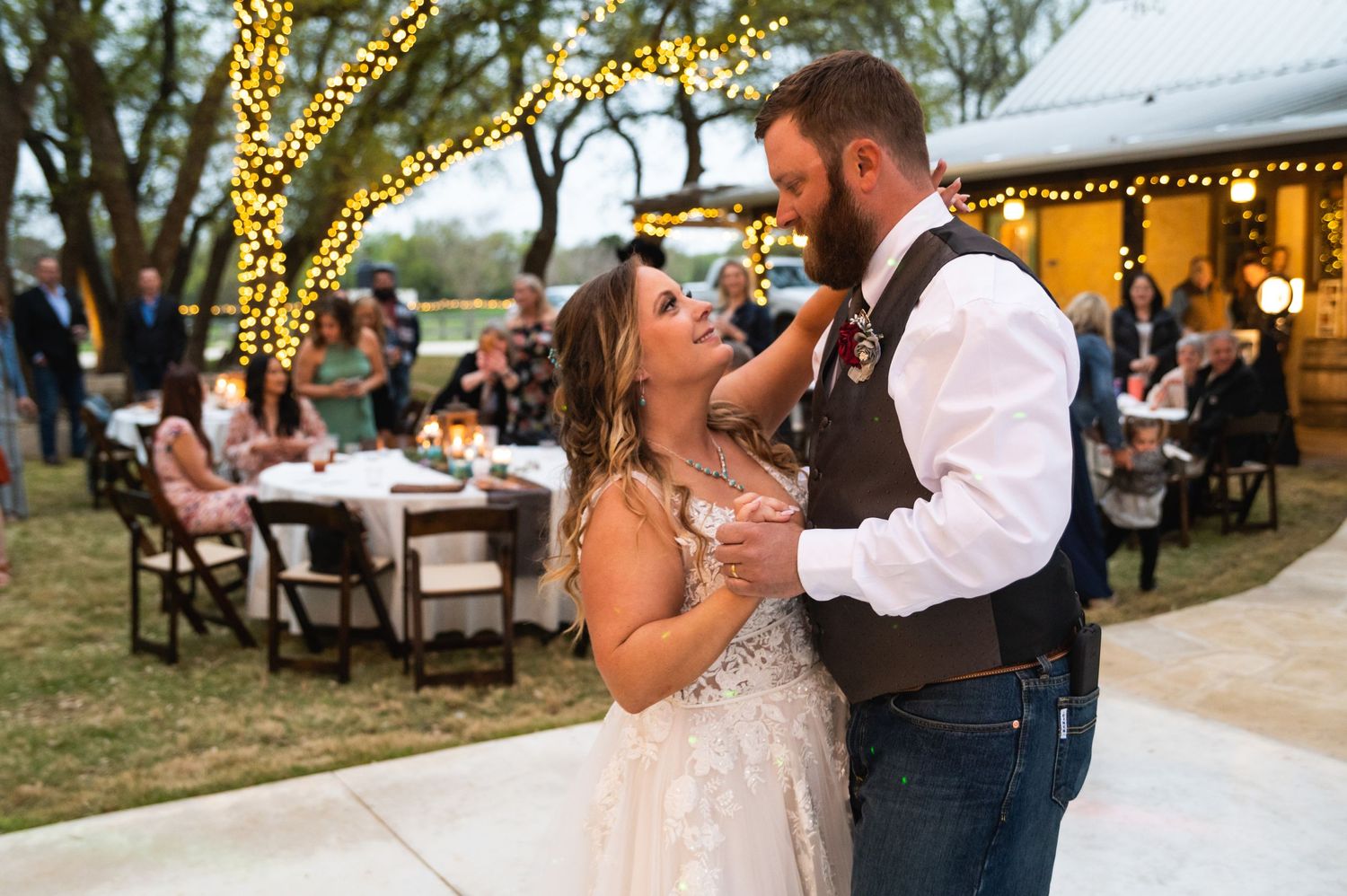 Wedding couple sharing an intimate dance moment at outdoor reception with string lights.