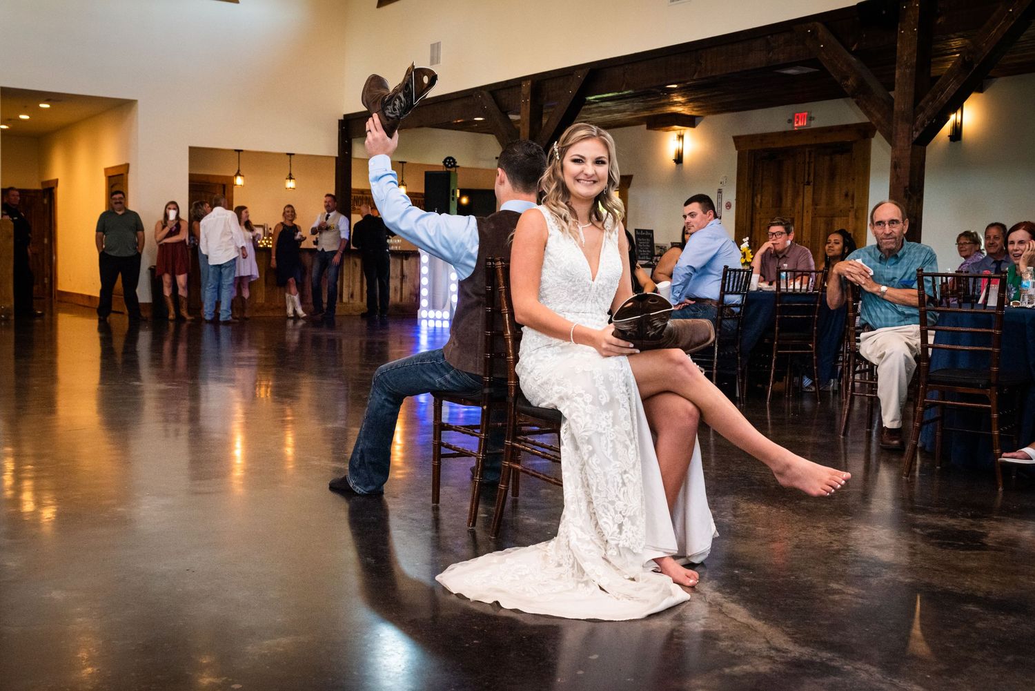Bride in lace dress performs fun dance move during wedding reception celebration.