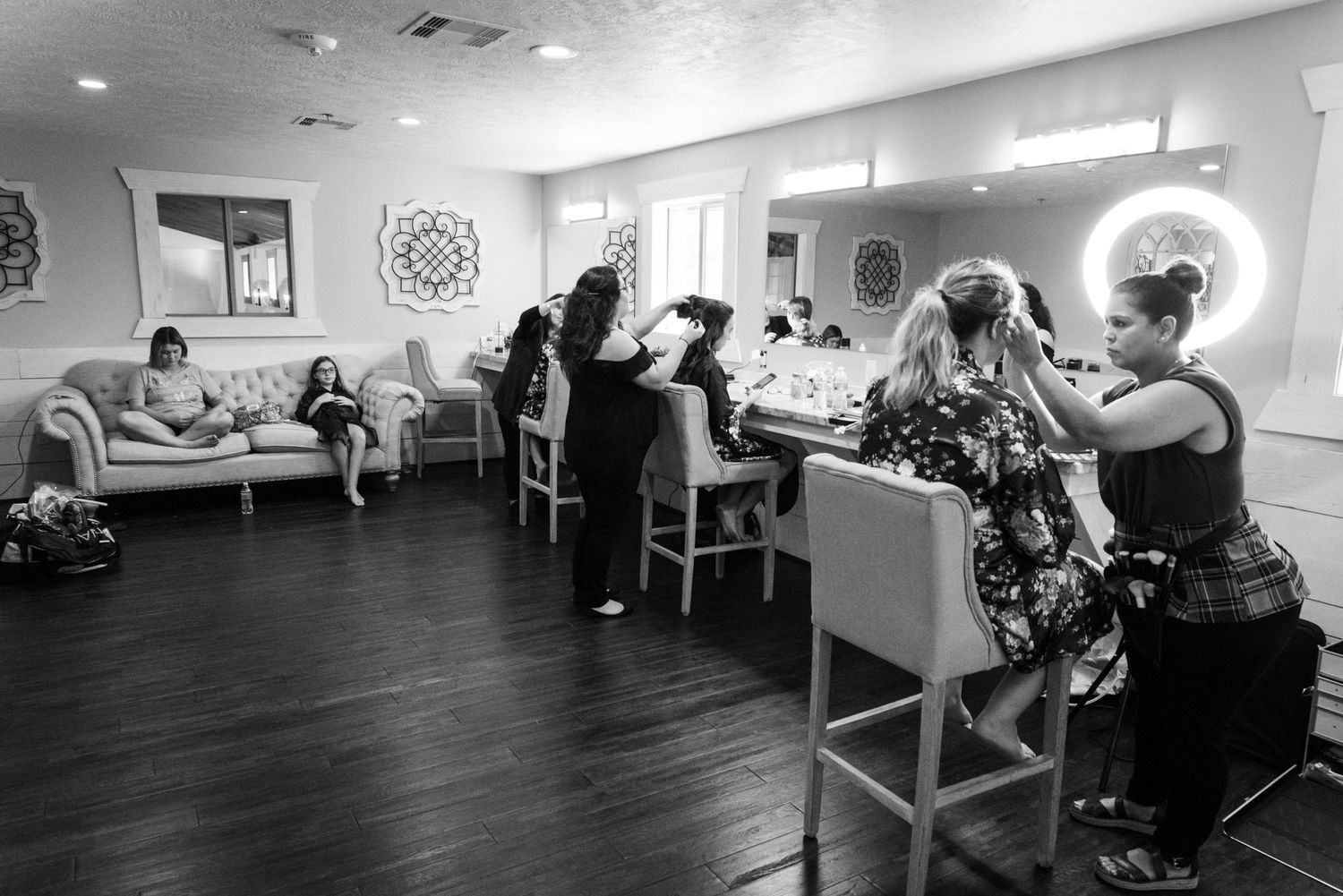 People gather in a modern salon with bright circular mirrors and comfortable seating.