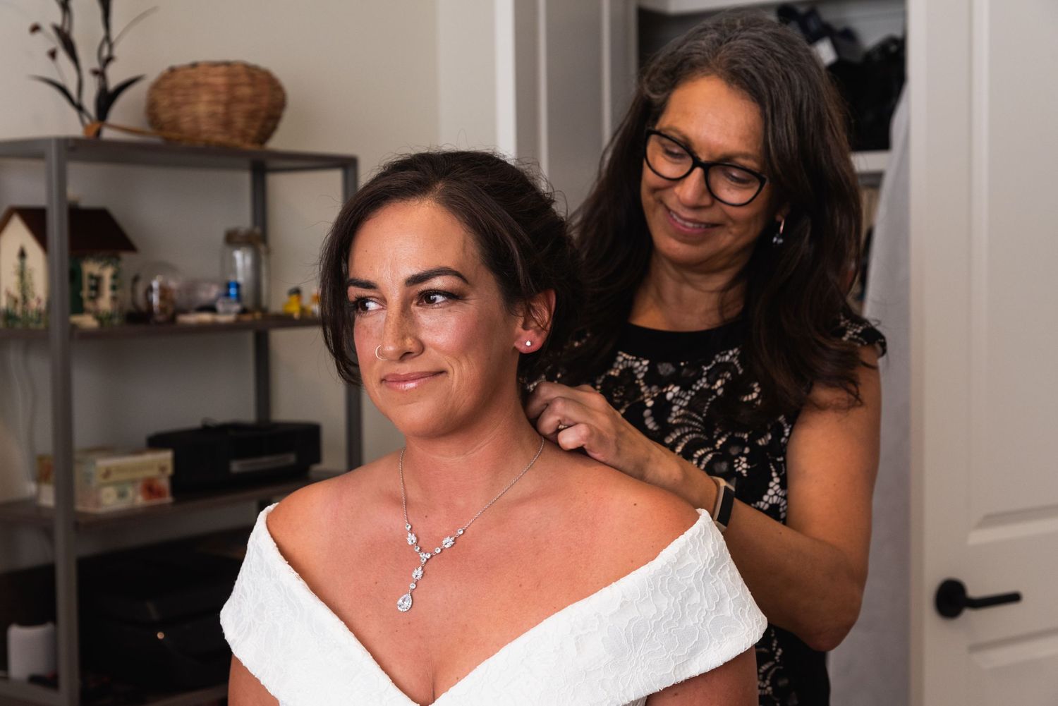Wedding preparations showing final dress and jewelry adjustments indoors.