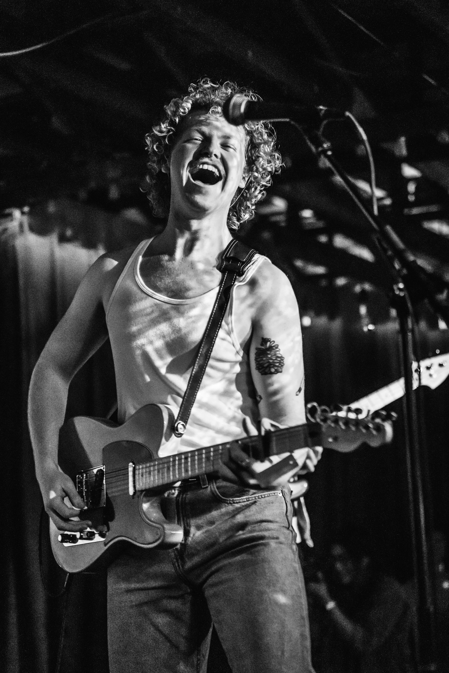 A passionate musician performs with an electric guitar on stage in black and white.