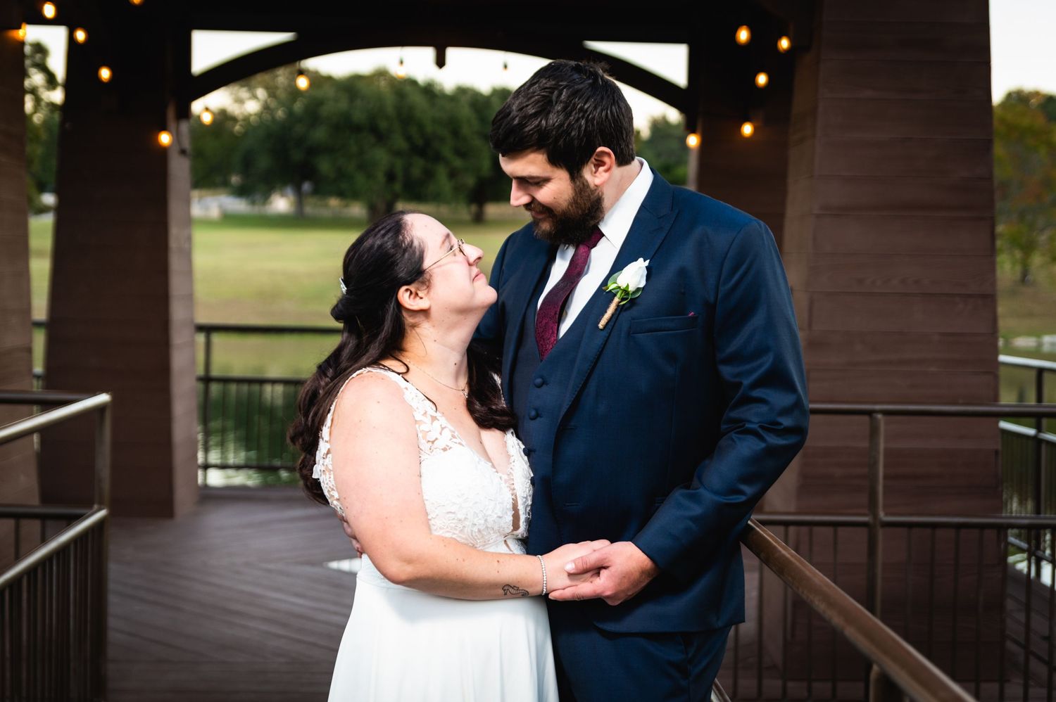 Intimate wedding moment captured under a covered wooden deck with string lights overhead.