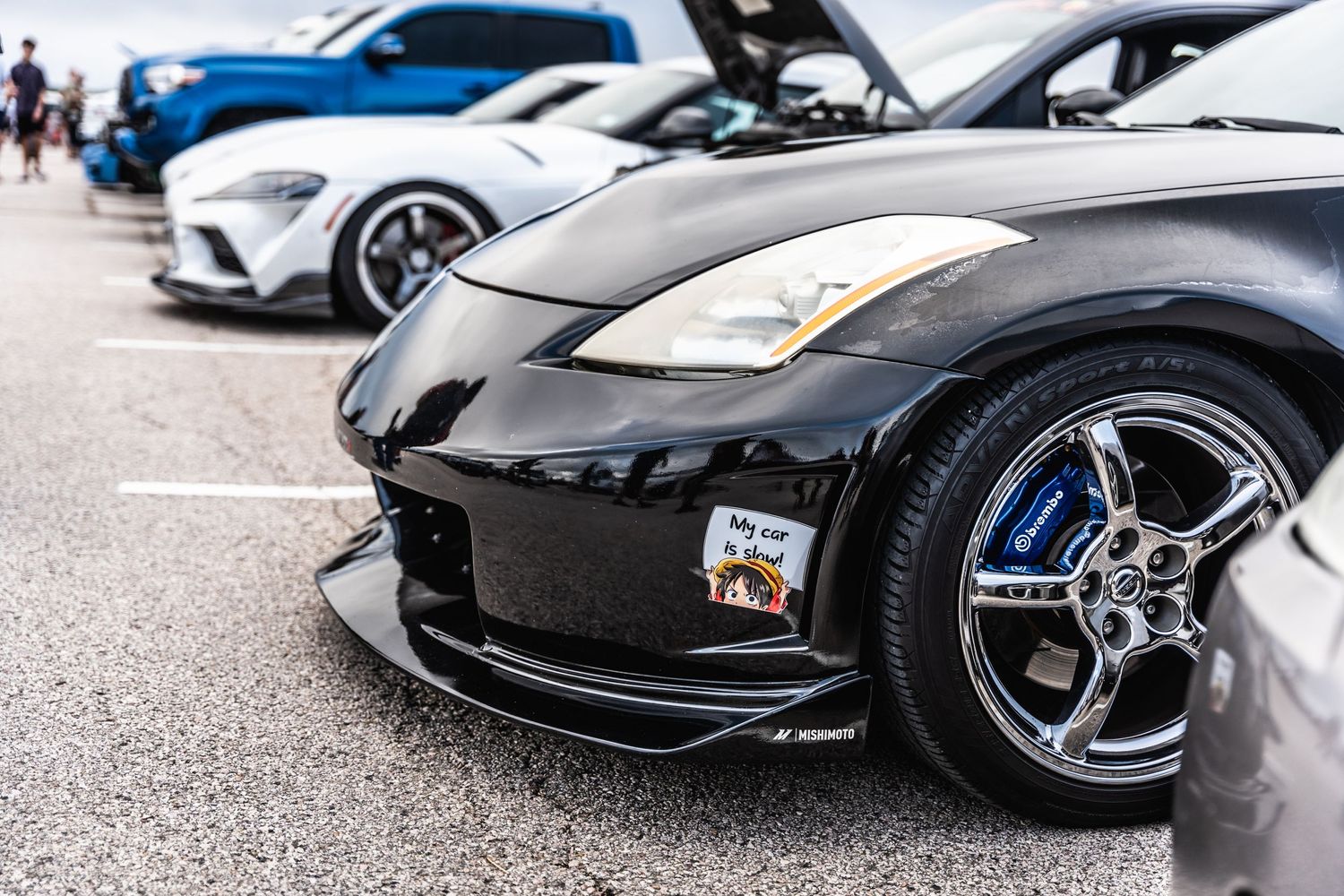 Close-up front view of black Nissan 350Z with custom wheels at car show.