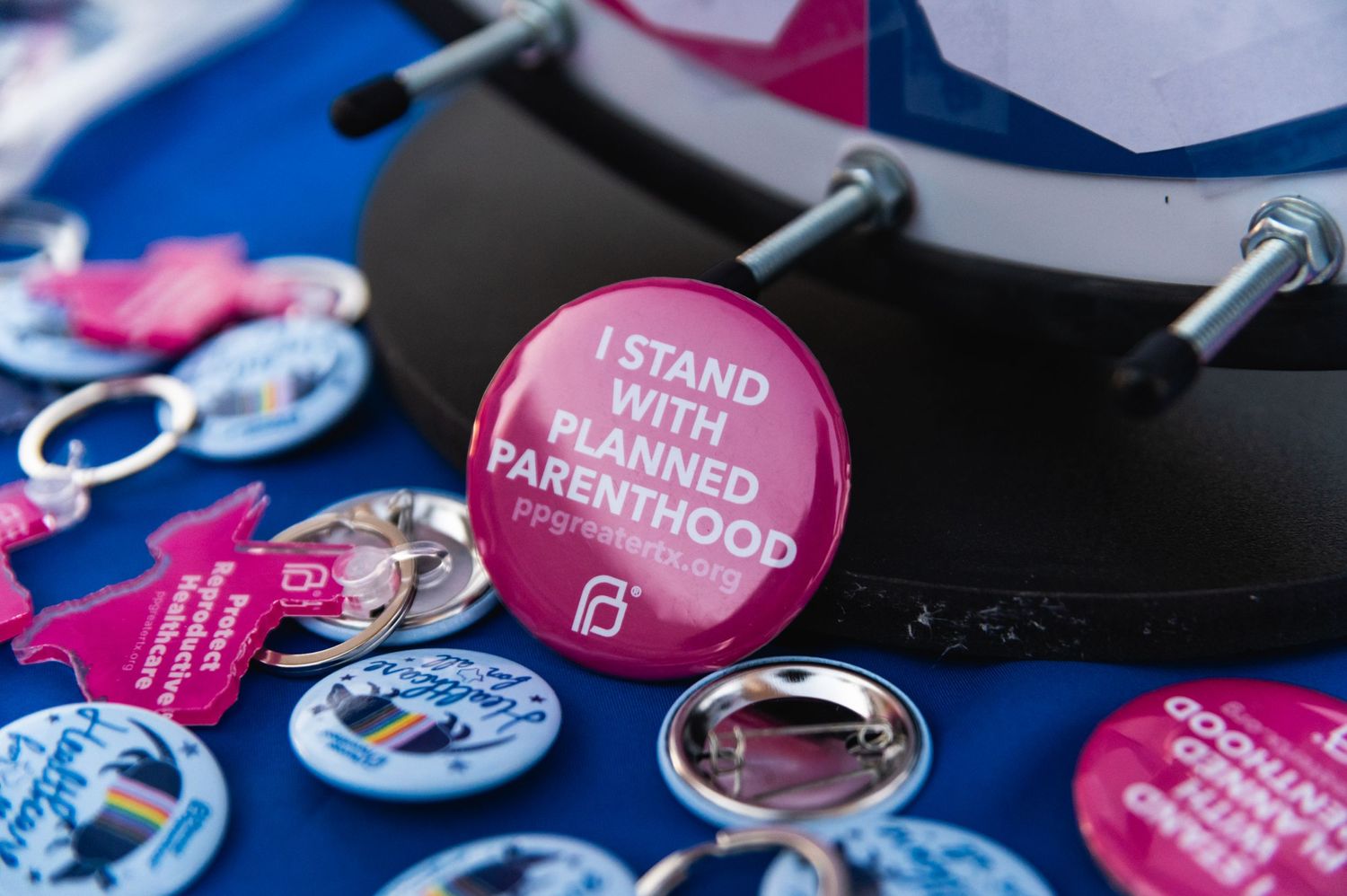 Political advocacy buttons and pins displayed on blue background.