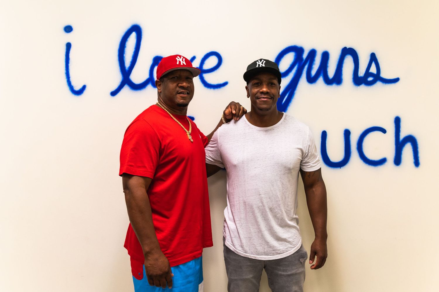 Two people posing in front of blue wall text at shooting range.