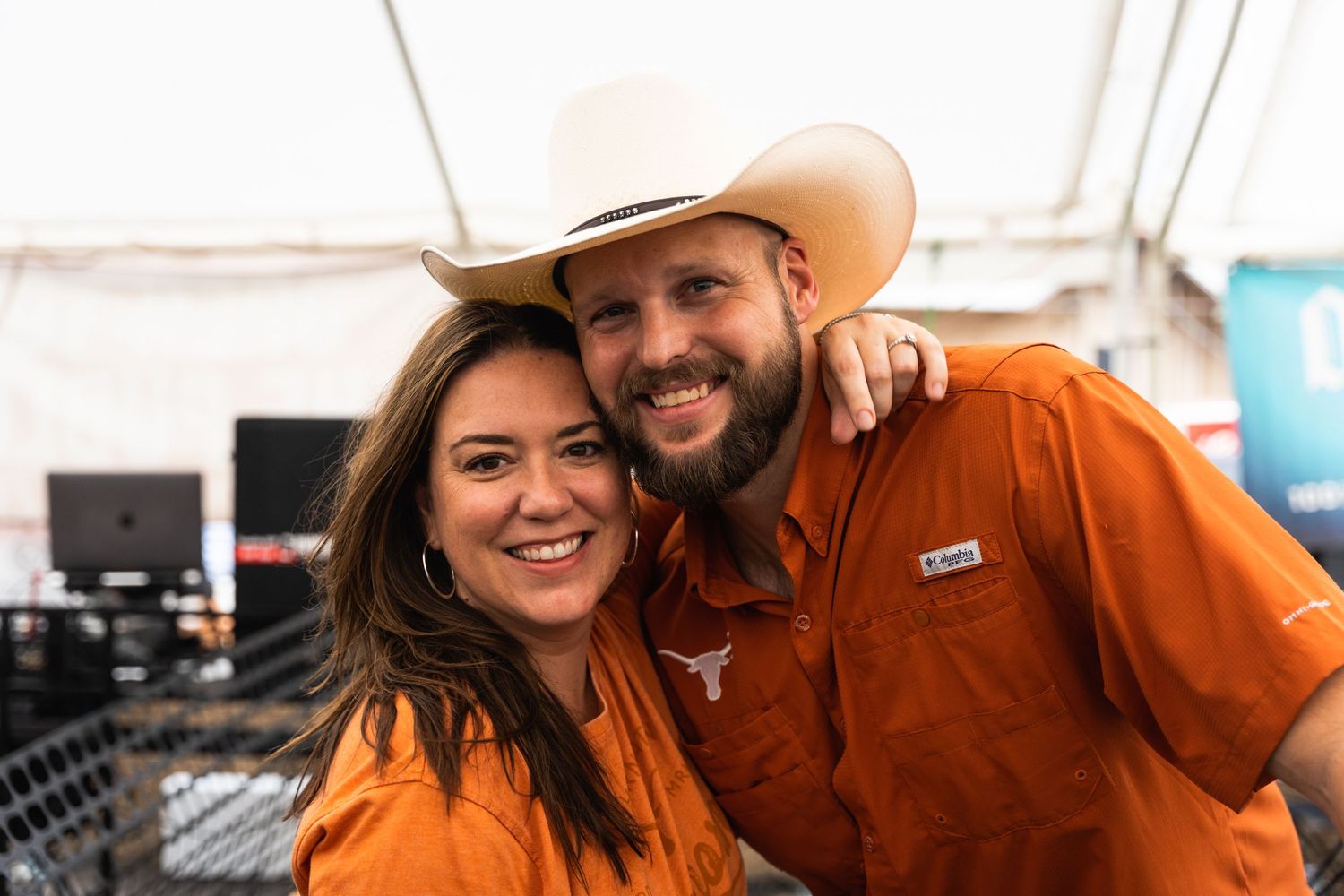 Two people in orange attire smiling together at outdoor festival.