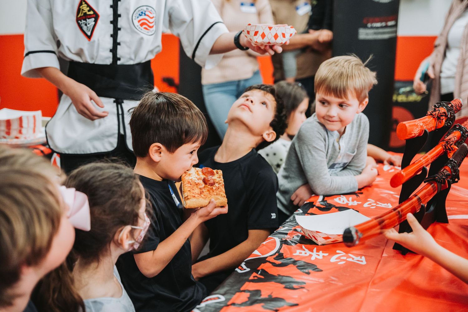 Students enjoying pizza and refreshments after martial arts practice in the training studio.