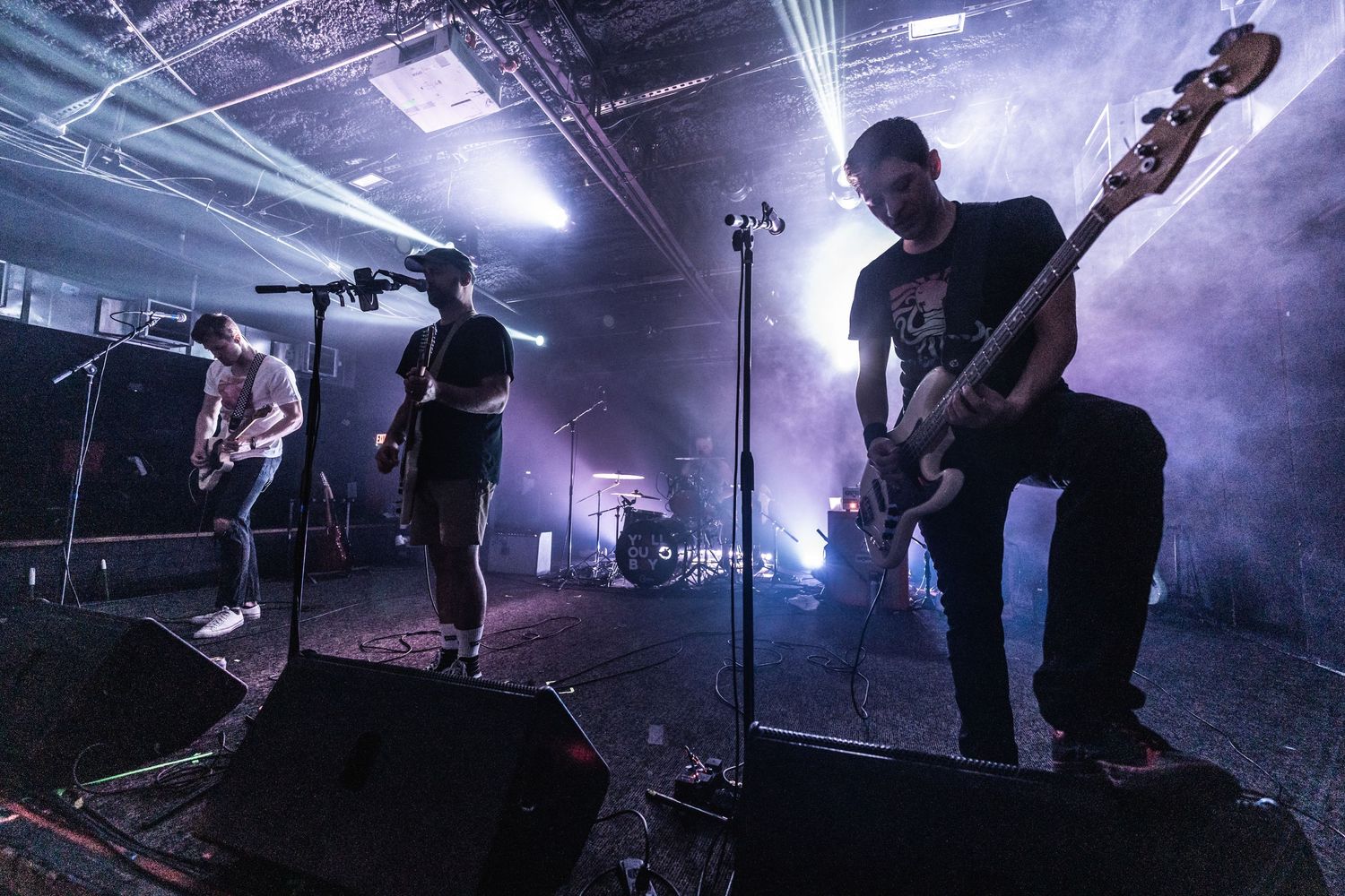 Silhouetted musicians perform on foggy stage with dramatic backlighting effects.