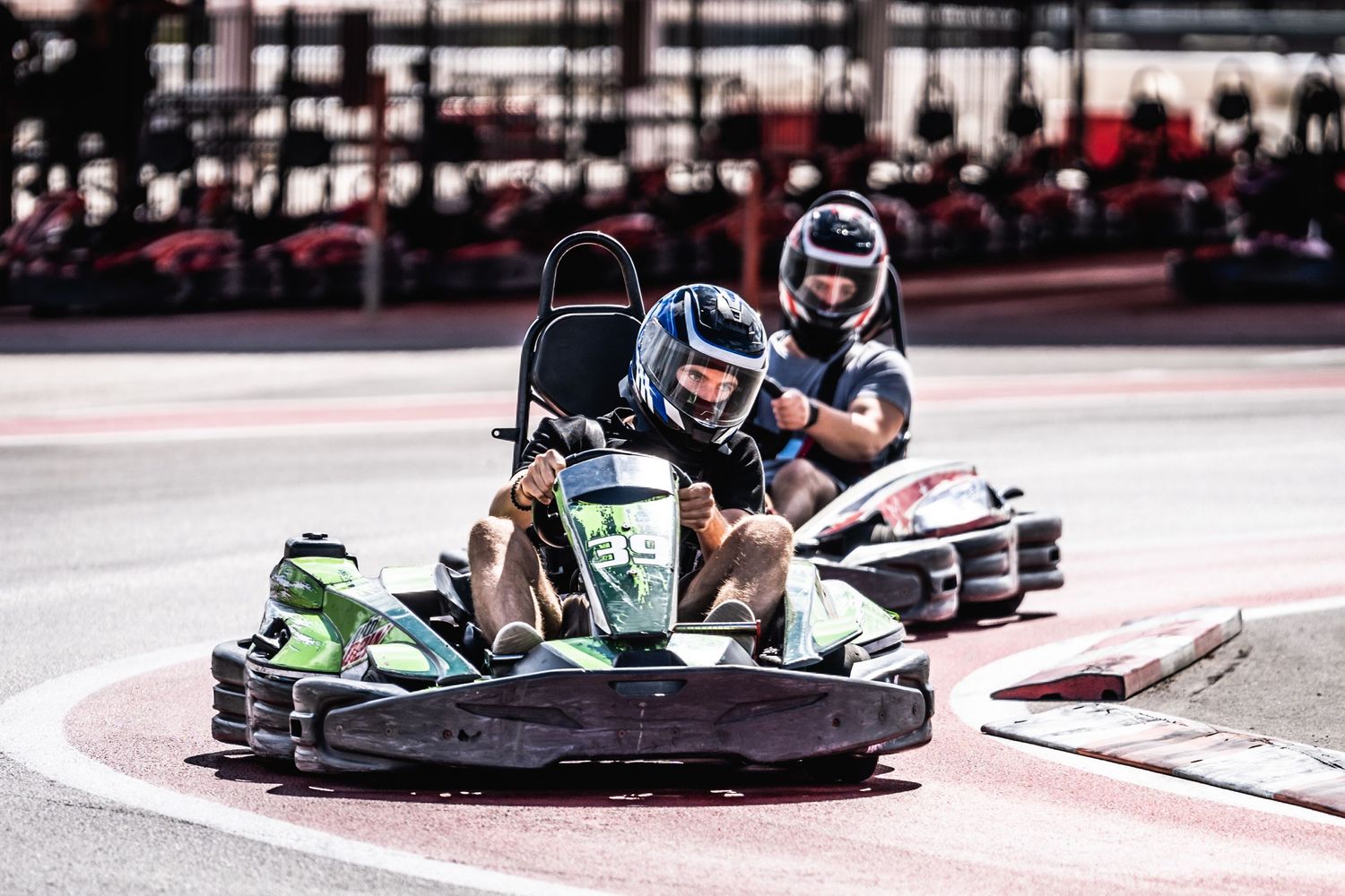 Two go-karts competing closely on outdoor karting track during race.