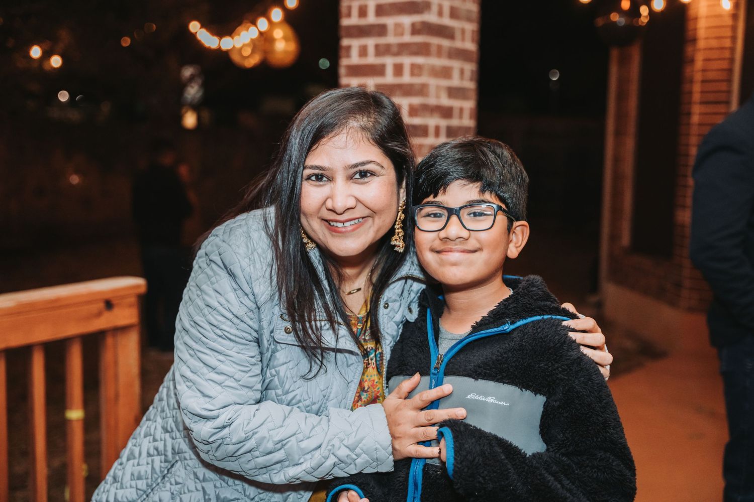 A cozy nighttime portrait on a porch with string lights illuminating the background.