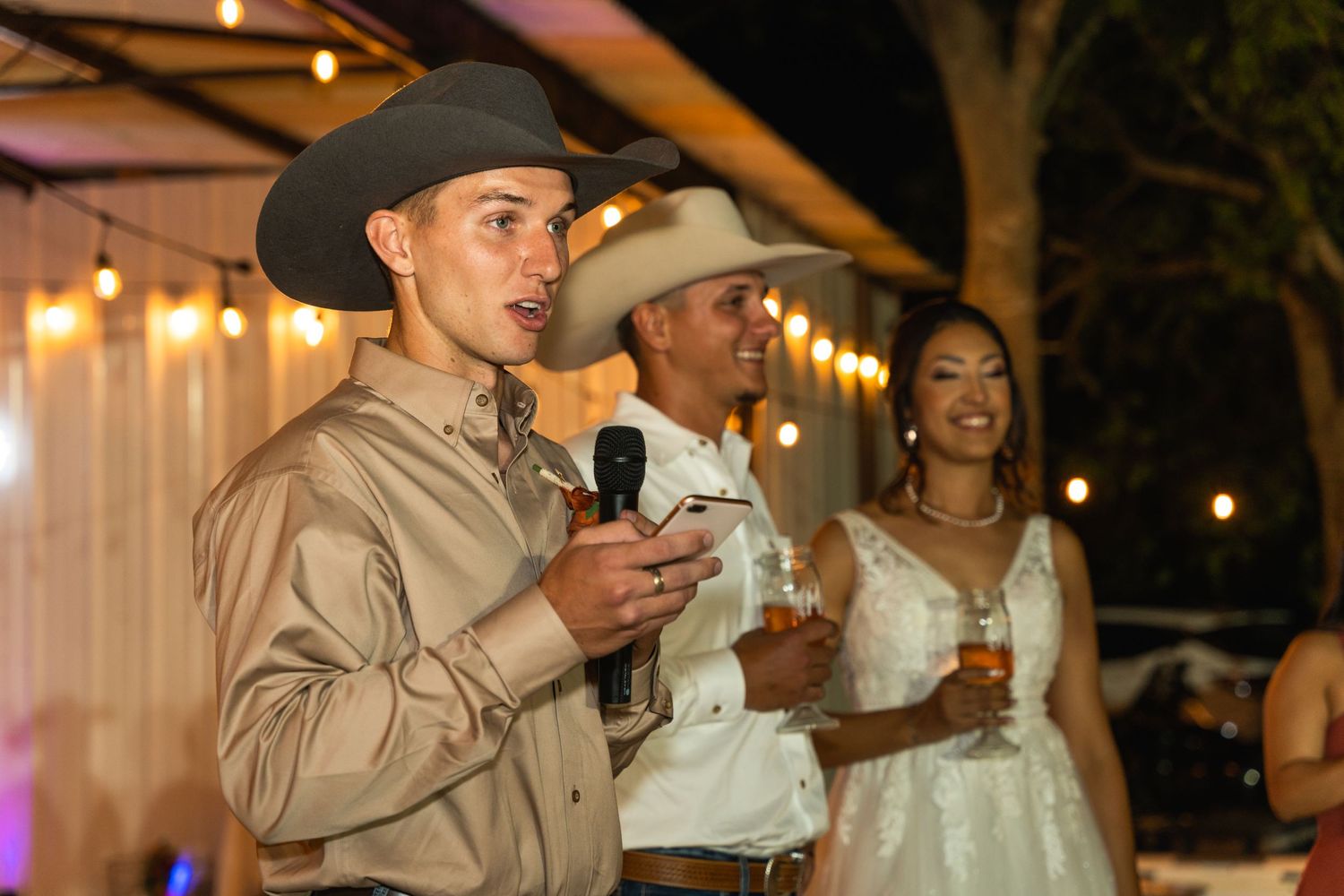 Evening wedding reception toasts with warm lighting and rustic decor.