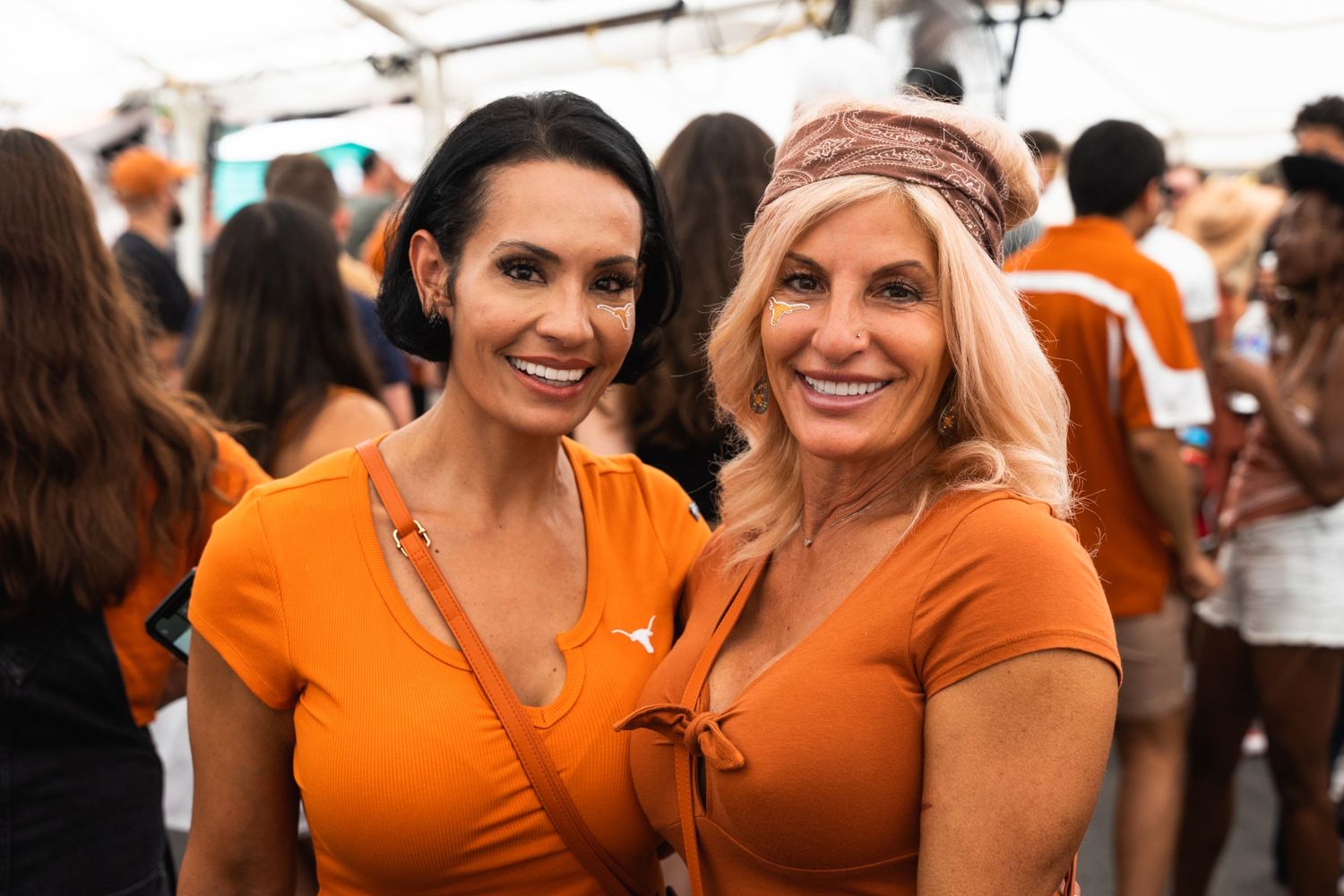 Two women wearing matching orange outfits at a sports event.