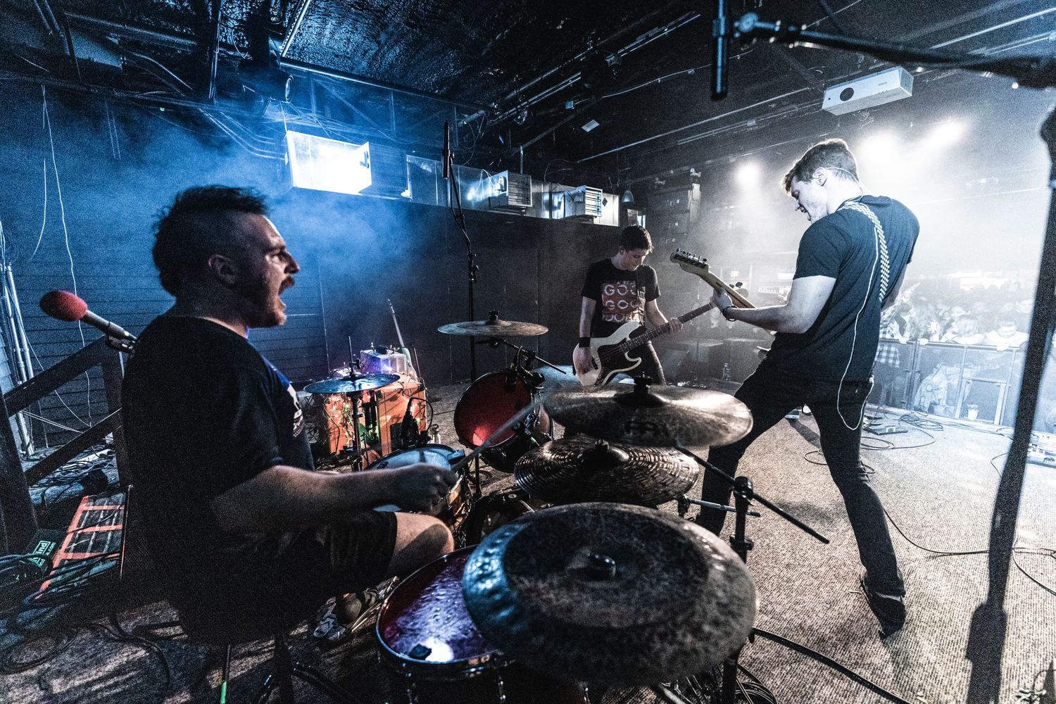 Band members performing on dimly lit stage with blue lighting effects.