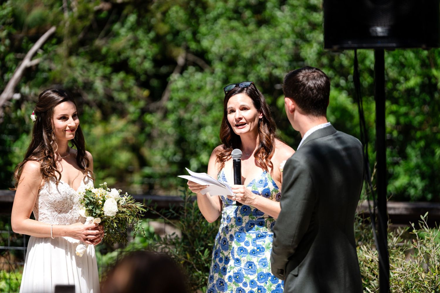Wedding party members share laughs during outdoor ceremony.