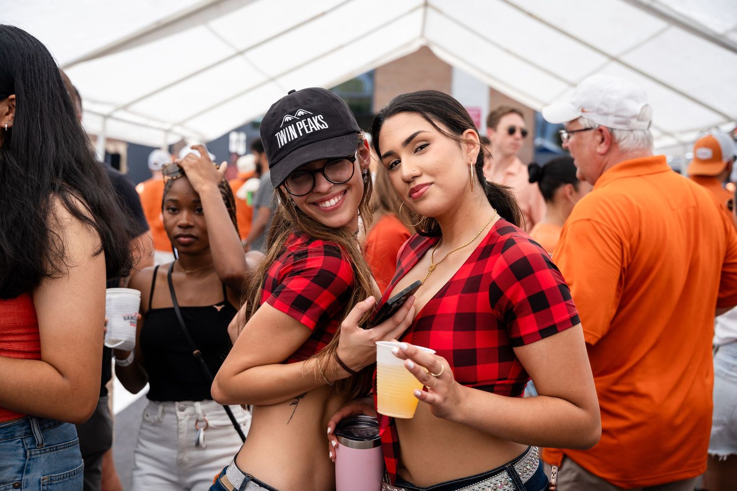 Friends in plaid shirts enjoying festivities at outdoor event.