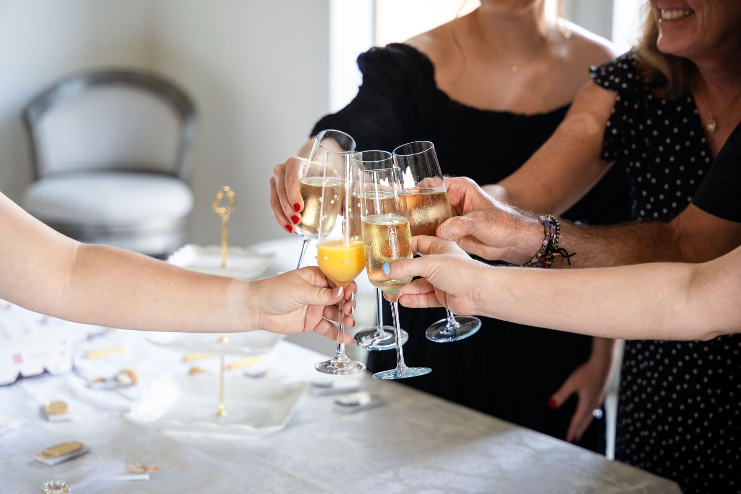 Several hands raise glasses of champagne for a celebratory toast at an elegant gathering.