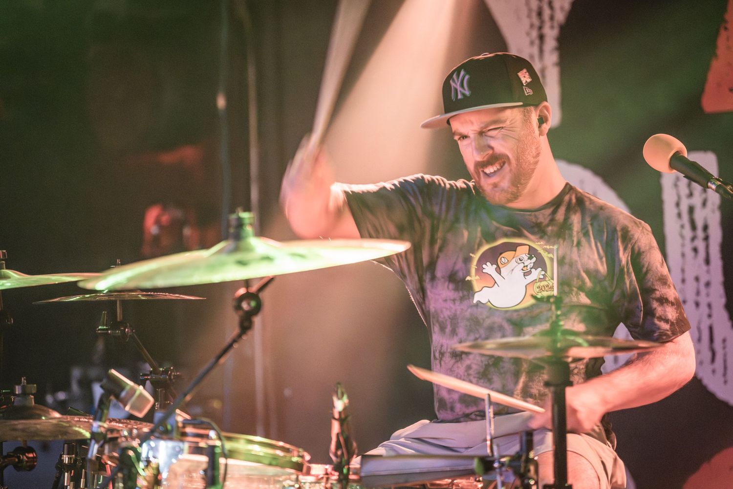 Energetic drummer playing on stage with motion blur and colorful lighting effects.