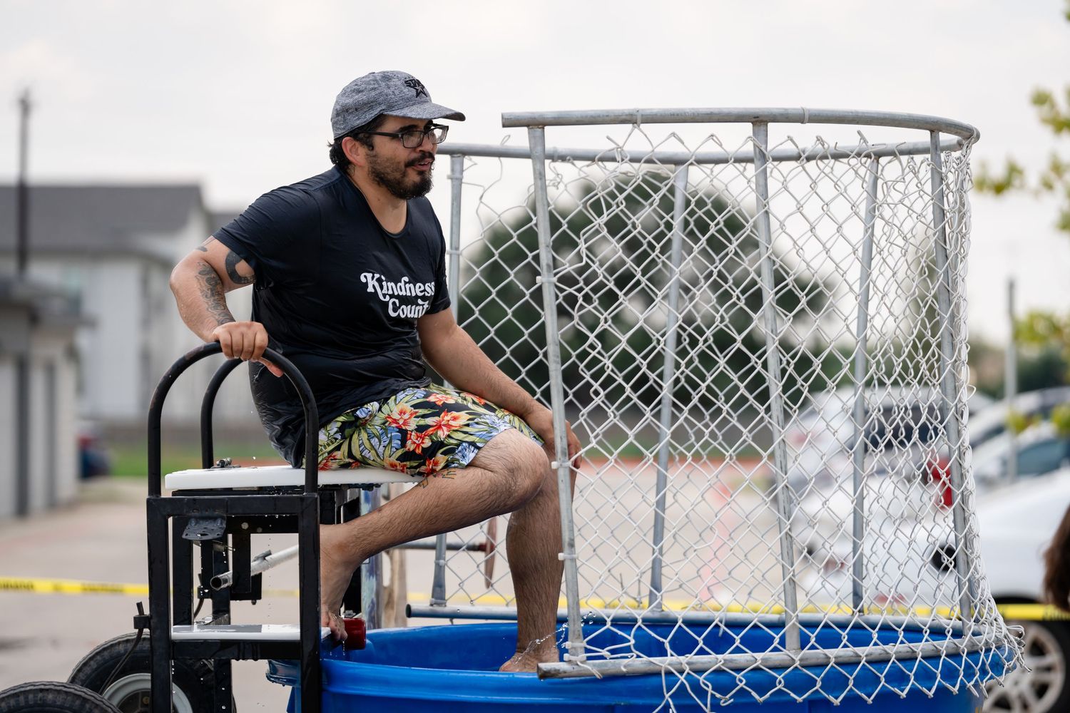 Person sitting on equipment next to a circular dunk tank setup at an outdoor event.