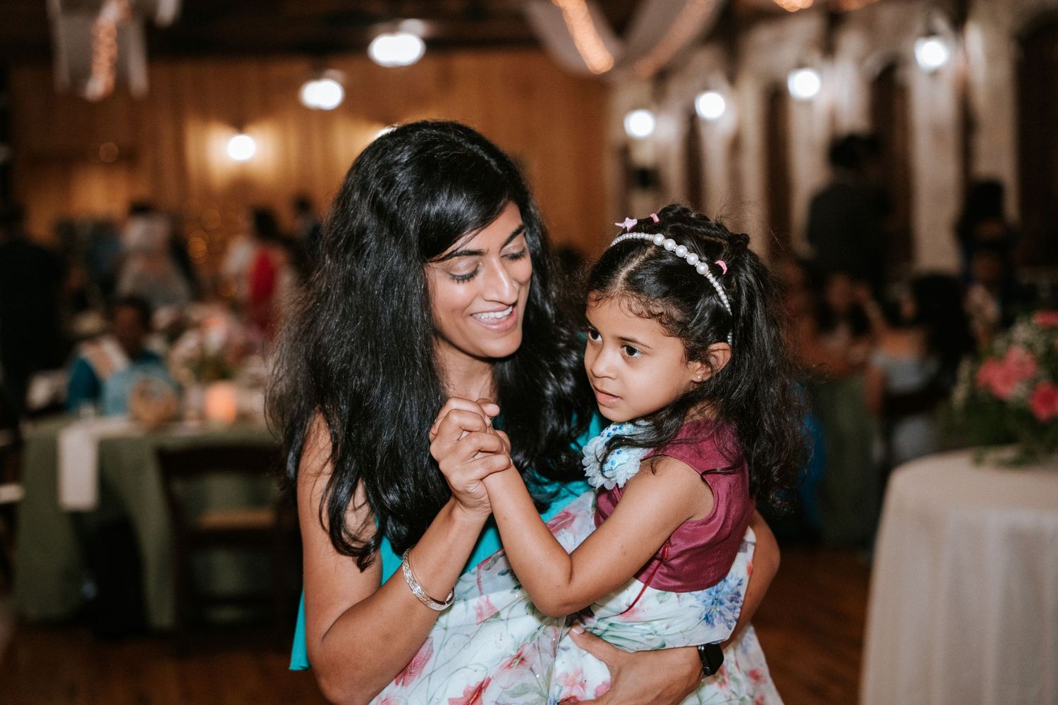 A celebratory dance moment between two guests in floral dresses at a wedding reception.