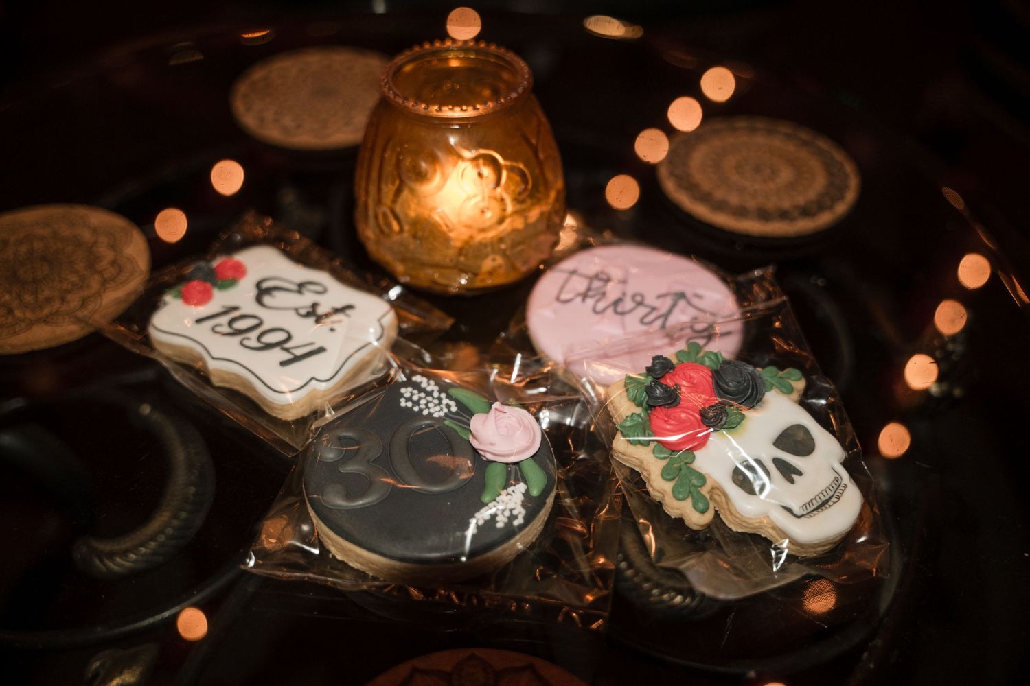 Decorated cookies displayed with a glowing lantern and bokeh lights in dark ambient setting.