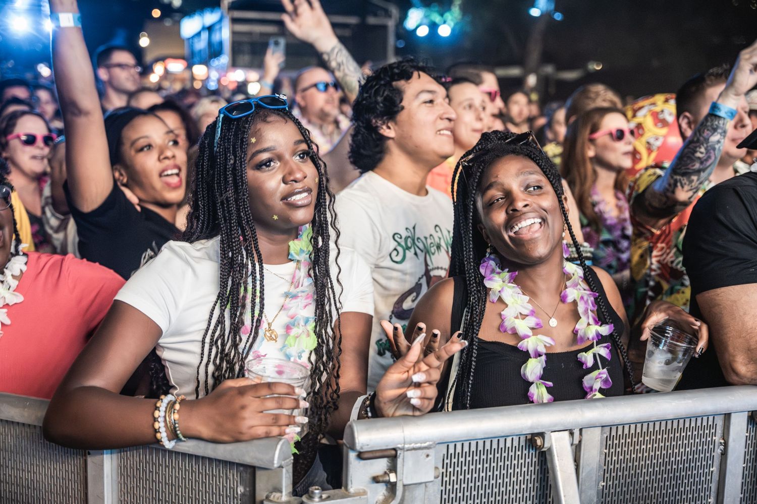 Concert-goers at front barrier react excitedly to performance at outdoor music festival.