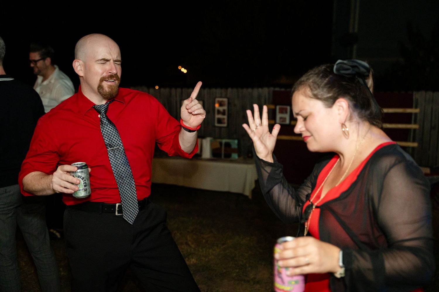 Party guests dancing and celebrating at nighttime wedding reception.